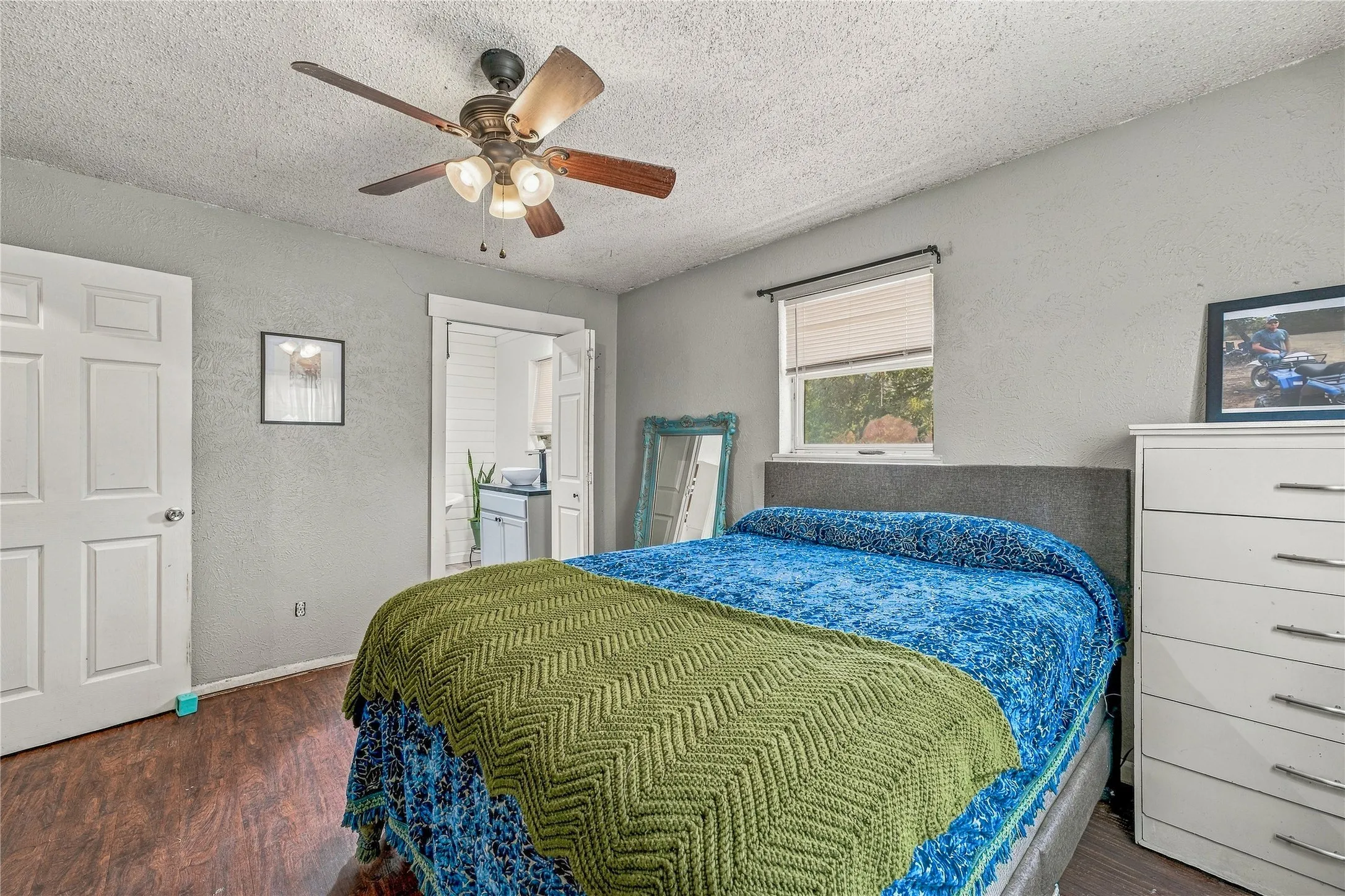 Wood-finish flooring, ceiling fan with light fixture, and a window with blinds