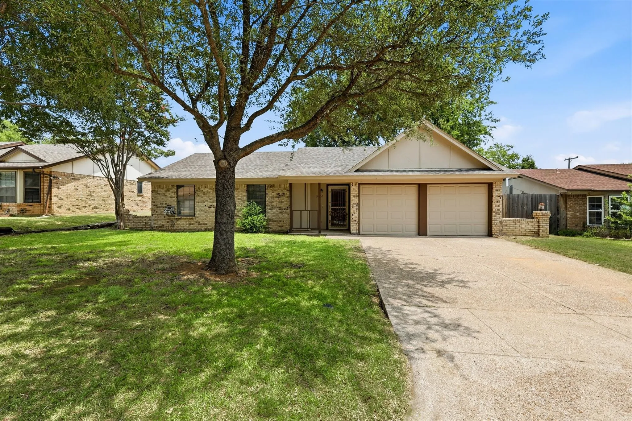 Ranch-style residence featuring a brick facade, a two-car garage, and a concrete driveway