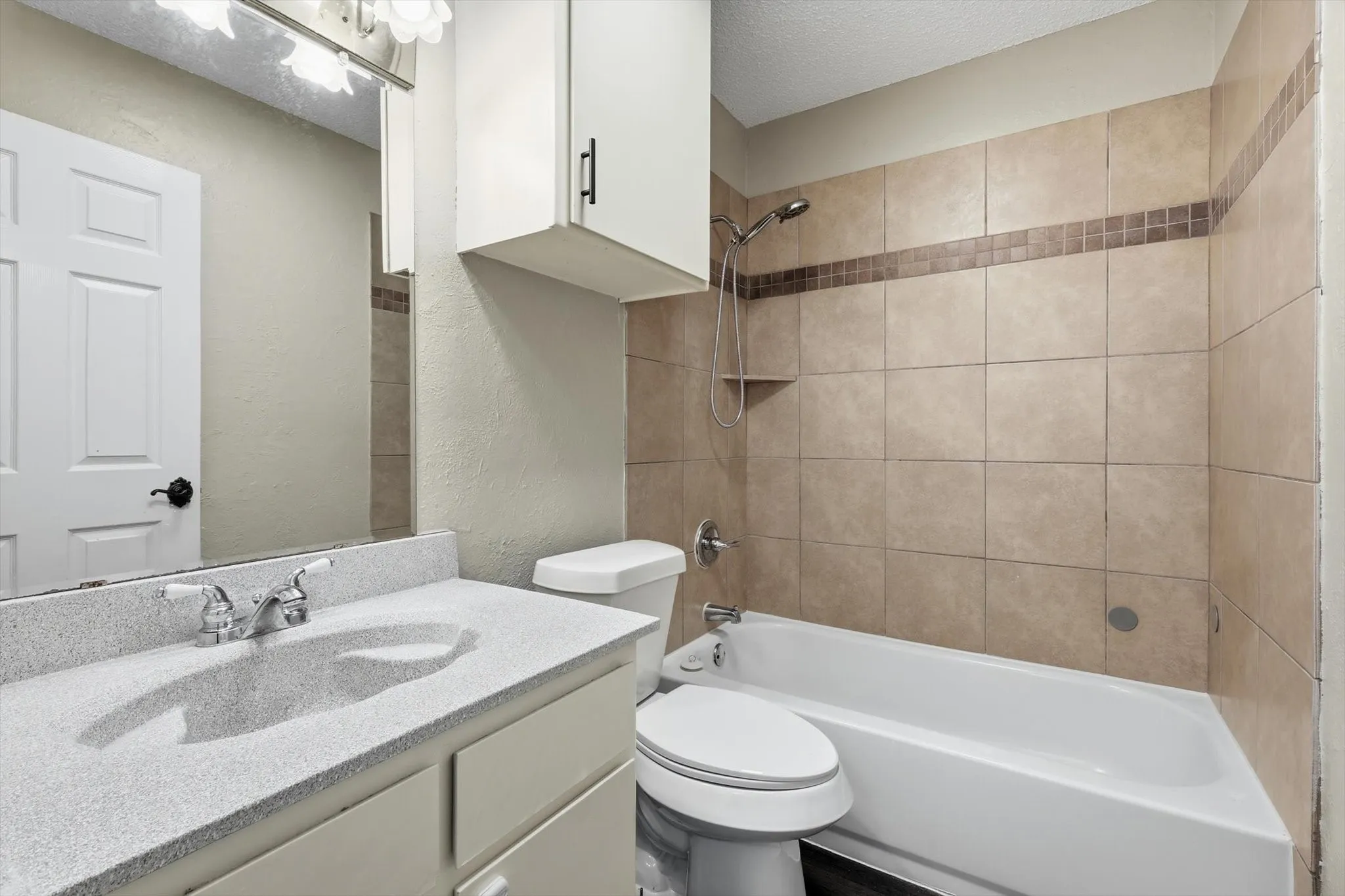 Bathroom featuring a white vanity with an integrated sink, polished chrome faucet, and overhead cabinetry