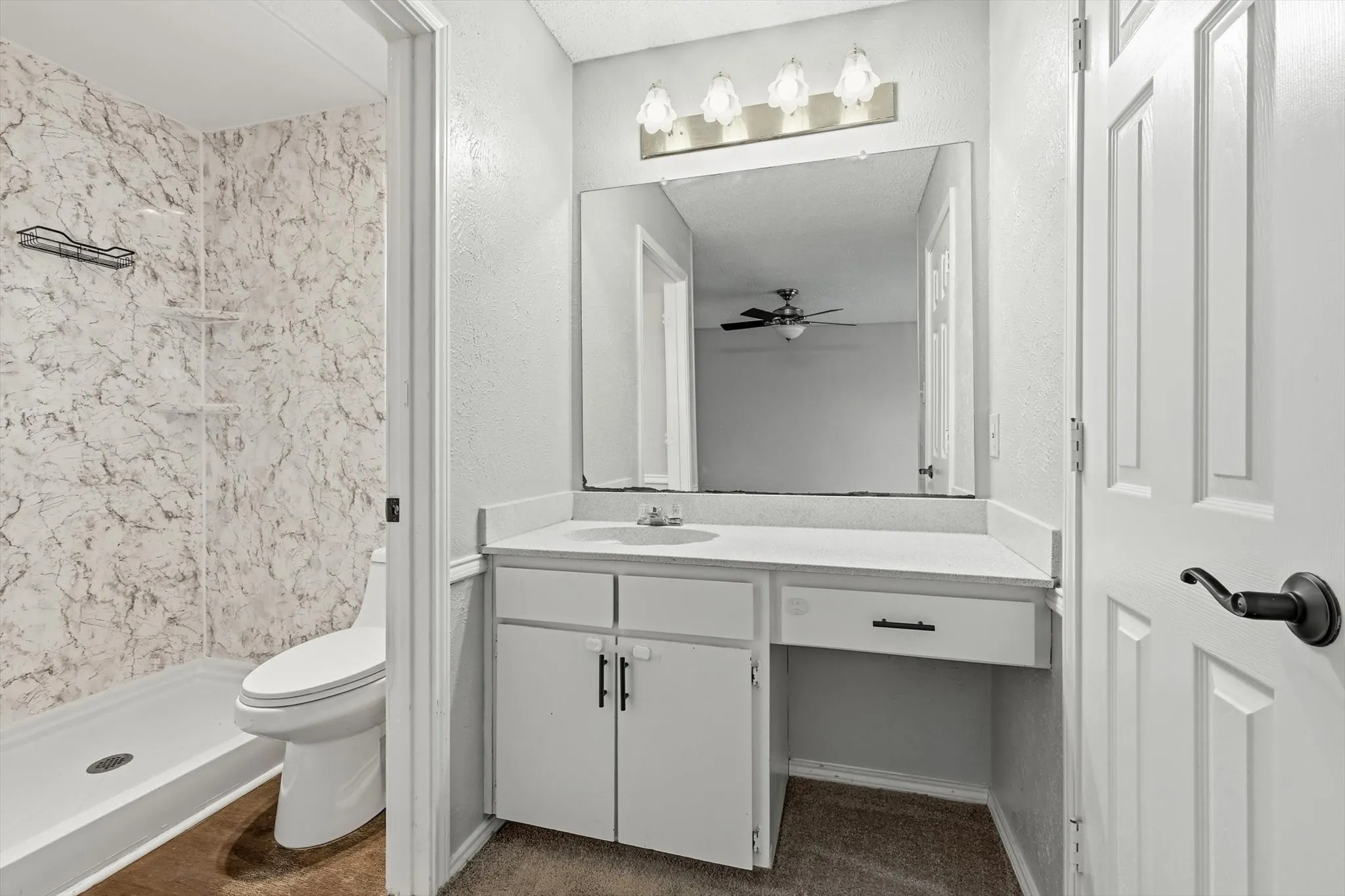 Bathroom featuring a vanity with white cabinetry, a built-in sink, a large mirror, and a three-light fixture