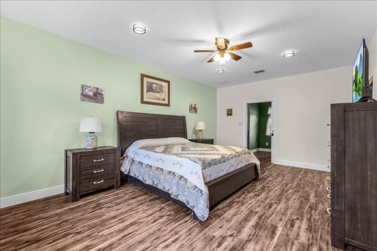Spacious bedroom featuring wood-finish flooring, recessed lighting, and a ceiling fan