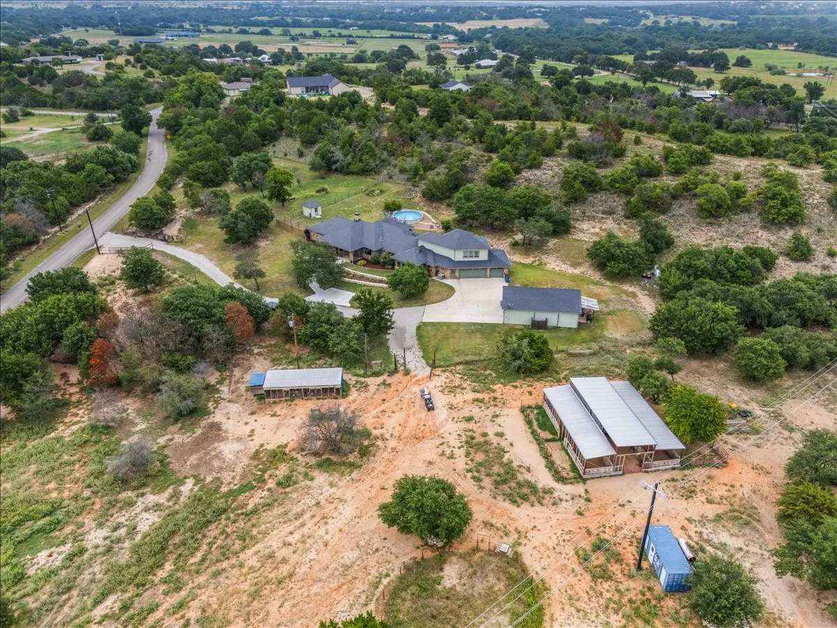 Expansive property featuring a main residence with an attached garage, a secondary structure, a swimming pool, and additional outbuildings