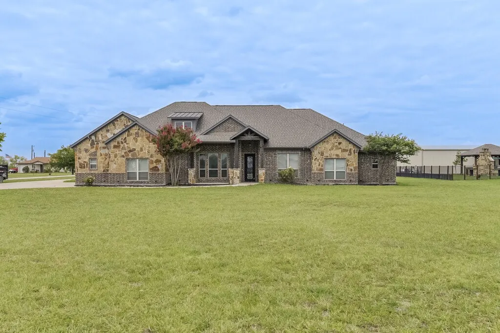 Expansive single-story residence featuring a combination of stone and brick exterior with a prominent gabled roofline