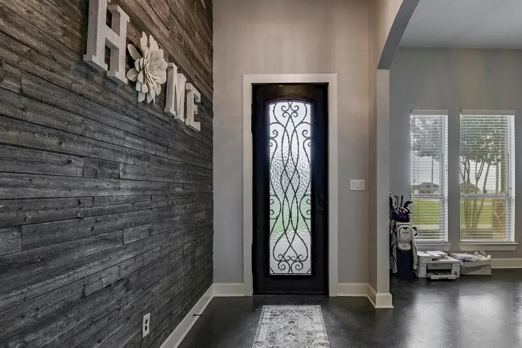 Entryway featuring a dark wood door with decorative wrought iron and privacy glass