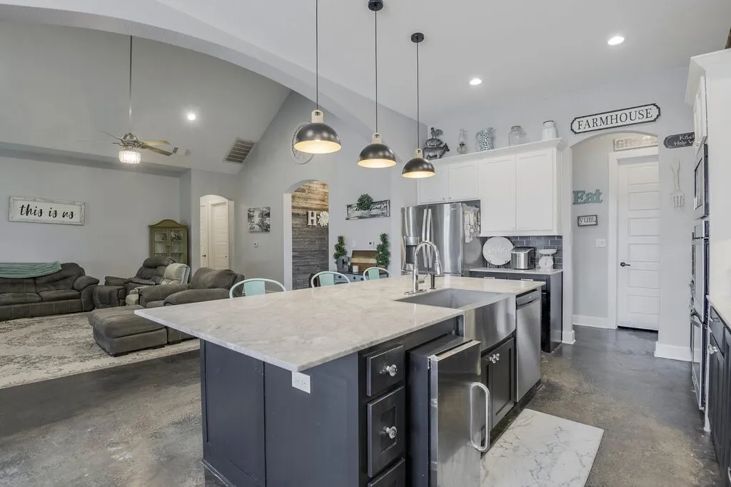 Kitchen island featuring a farmhouse sink, stainless steel appliances, and pendant lighting