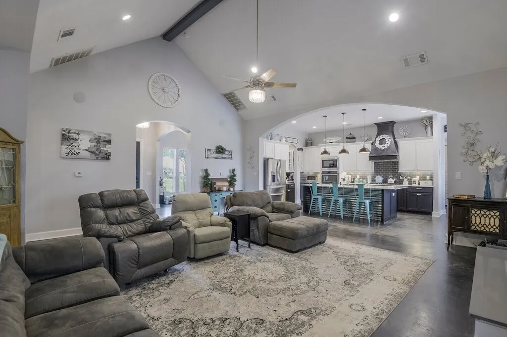 Spacious living area featuring a vaulted ceiling with exposed beam, recessed lighting, and a ceiling fan