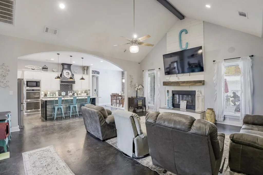 Spacious open-concept living area featuring high vaulted ceilings, recessed lighting, and dark concrete flooring