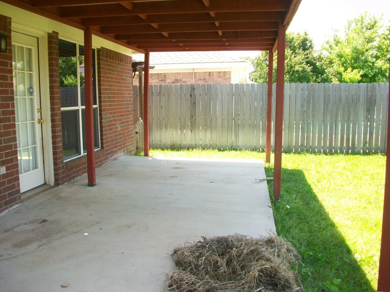 Covered concrete patio with wooden support beams and an exposed rafter ceiling