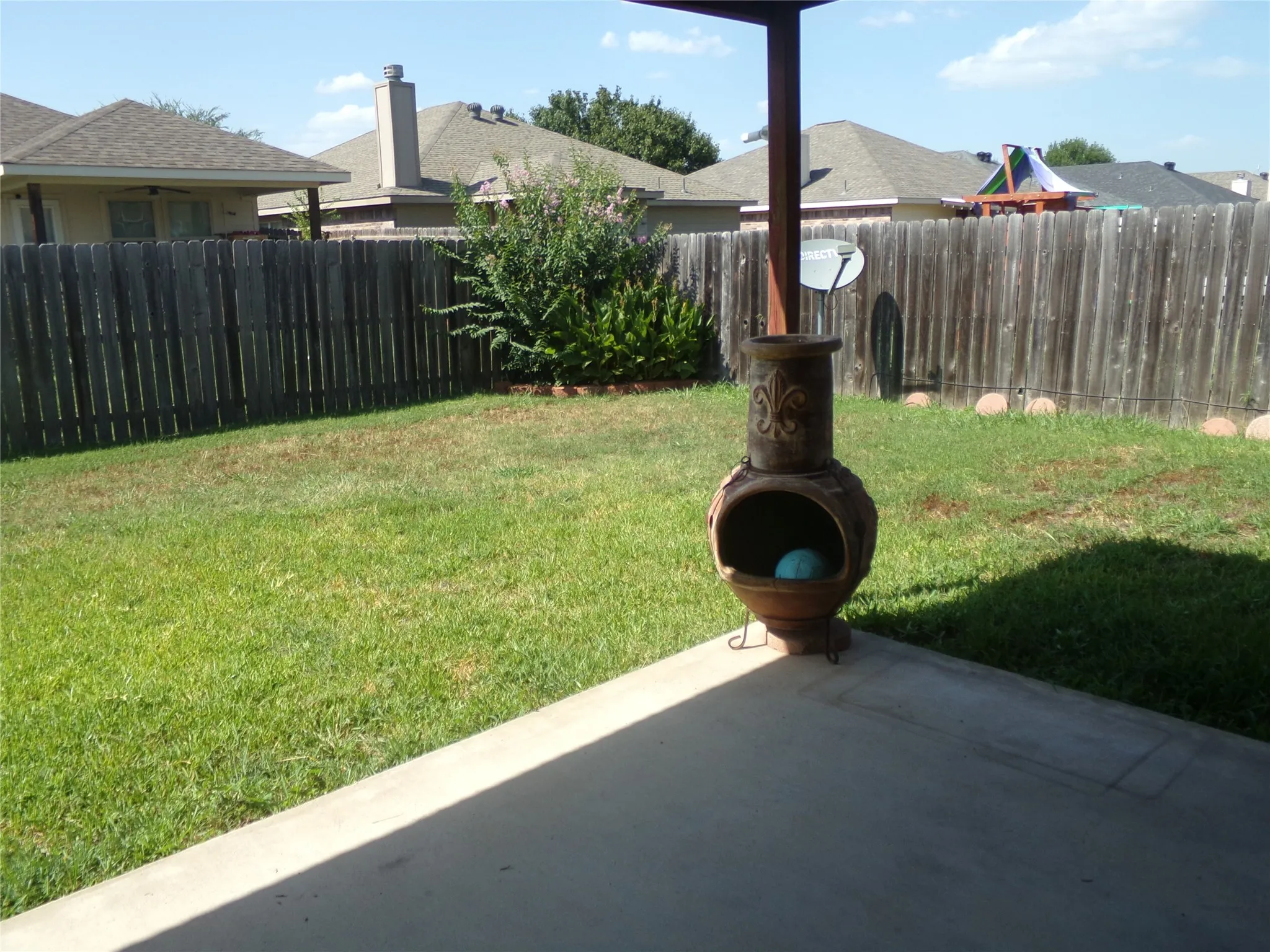 Expansive backyard featuring a lush lawn, privacy fencing, and a concrete patio pad