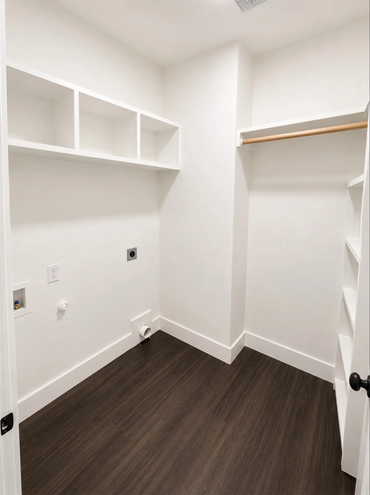 Dedicated utility room featuring dark wood-finish flooring, white baseboards, and bright white walls