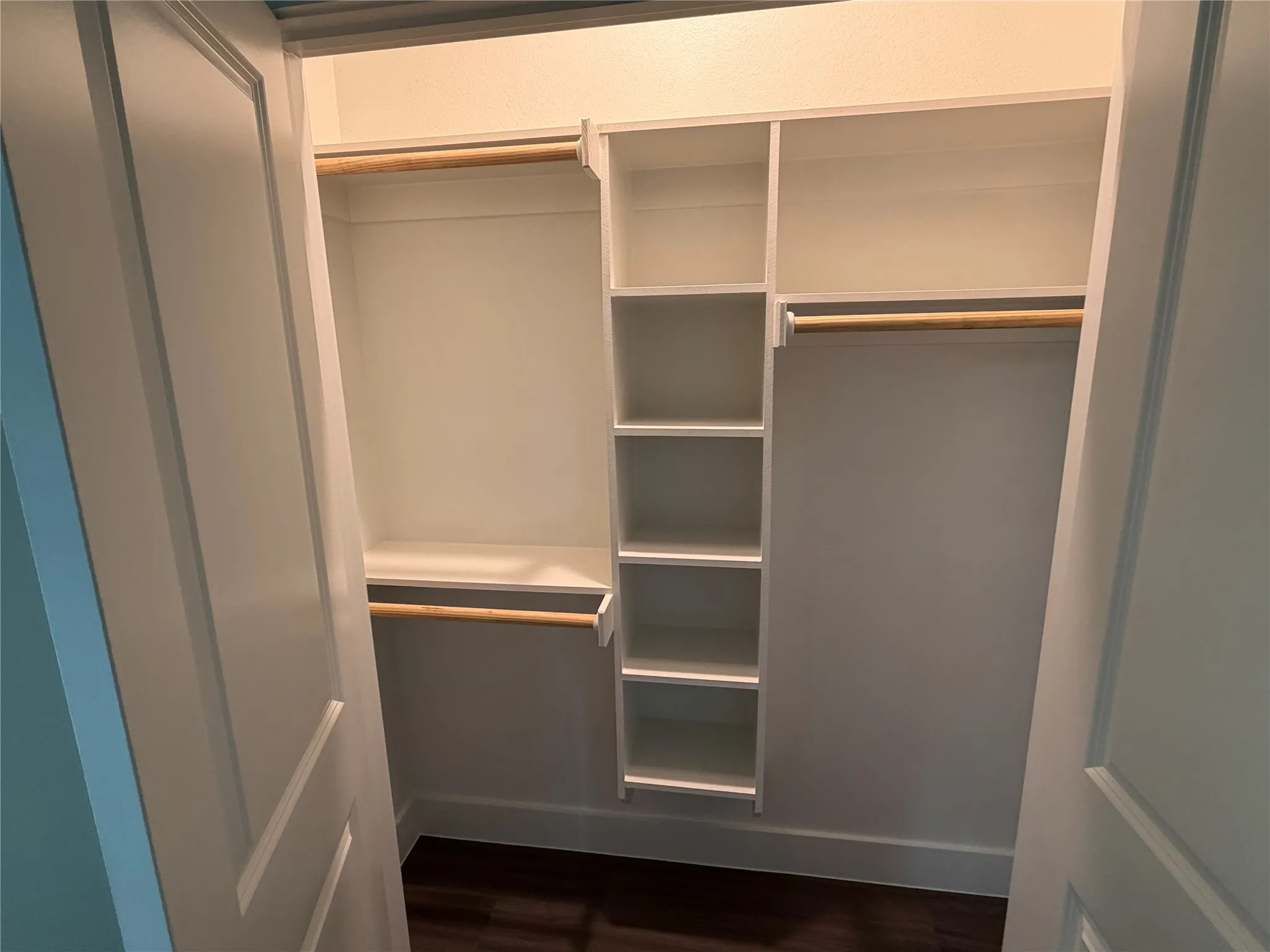 Built-in closet system featuring white shelving and two hanging rods
