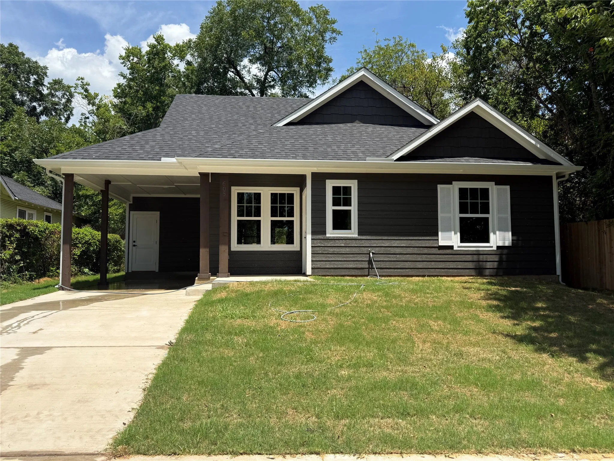 Contemporary residence featuring dark gray horizontal siding, white trim, and a dark shingled roof