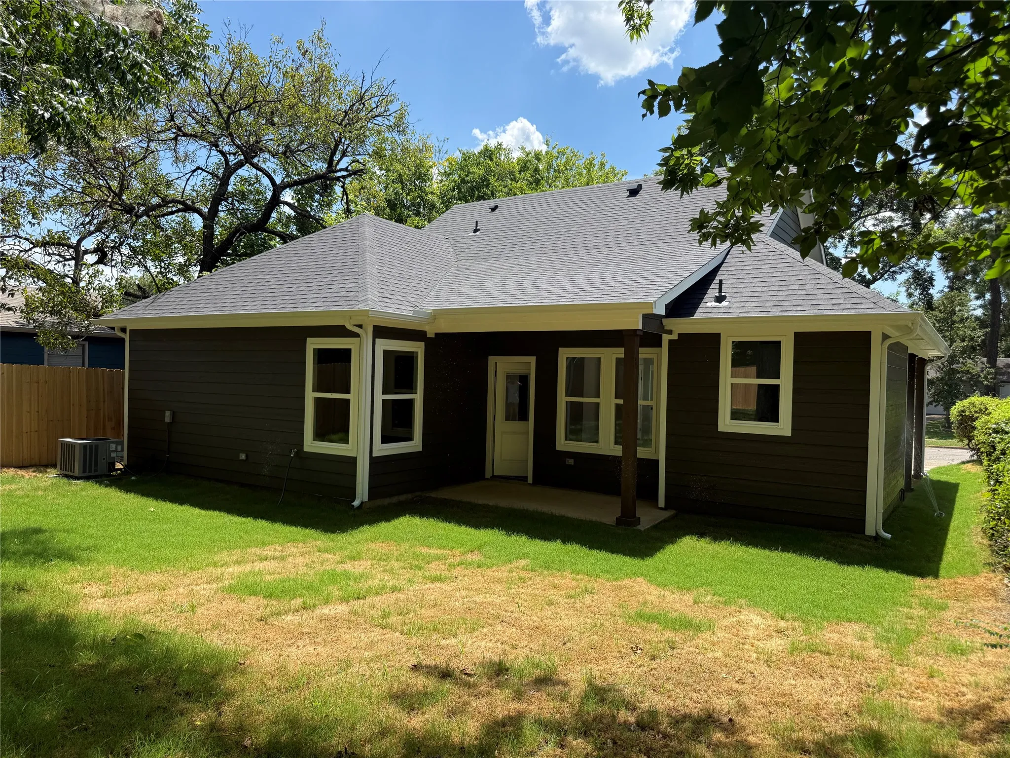 Rear exterior featuring dark siding, white trim, and a shingle roof