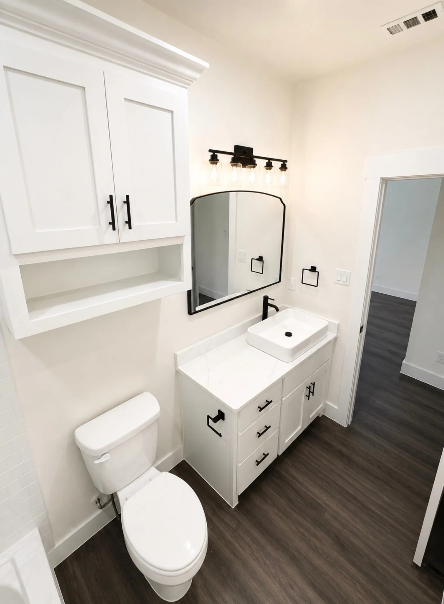 Modern bathroom featuring a white vanity with a rectangular vessel sink, white countertop, and dark wood-finish flooring