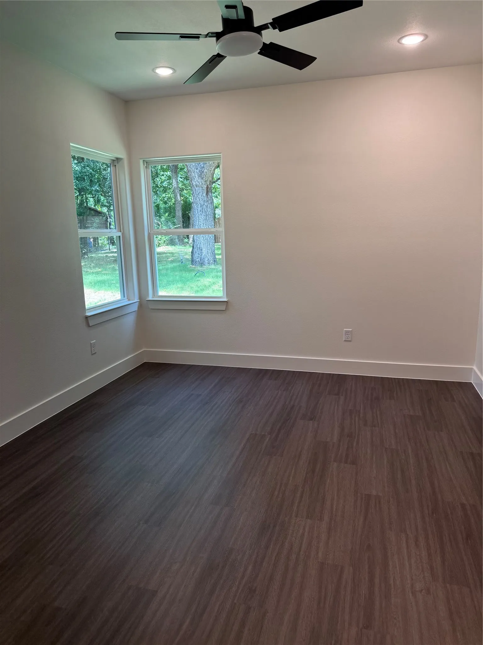 Room featuring wood-finish flooring, two windows, recessed lighting, and a ceiling fan with integrated light