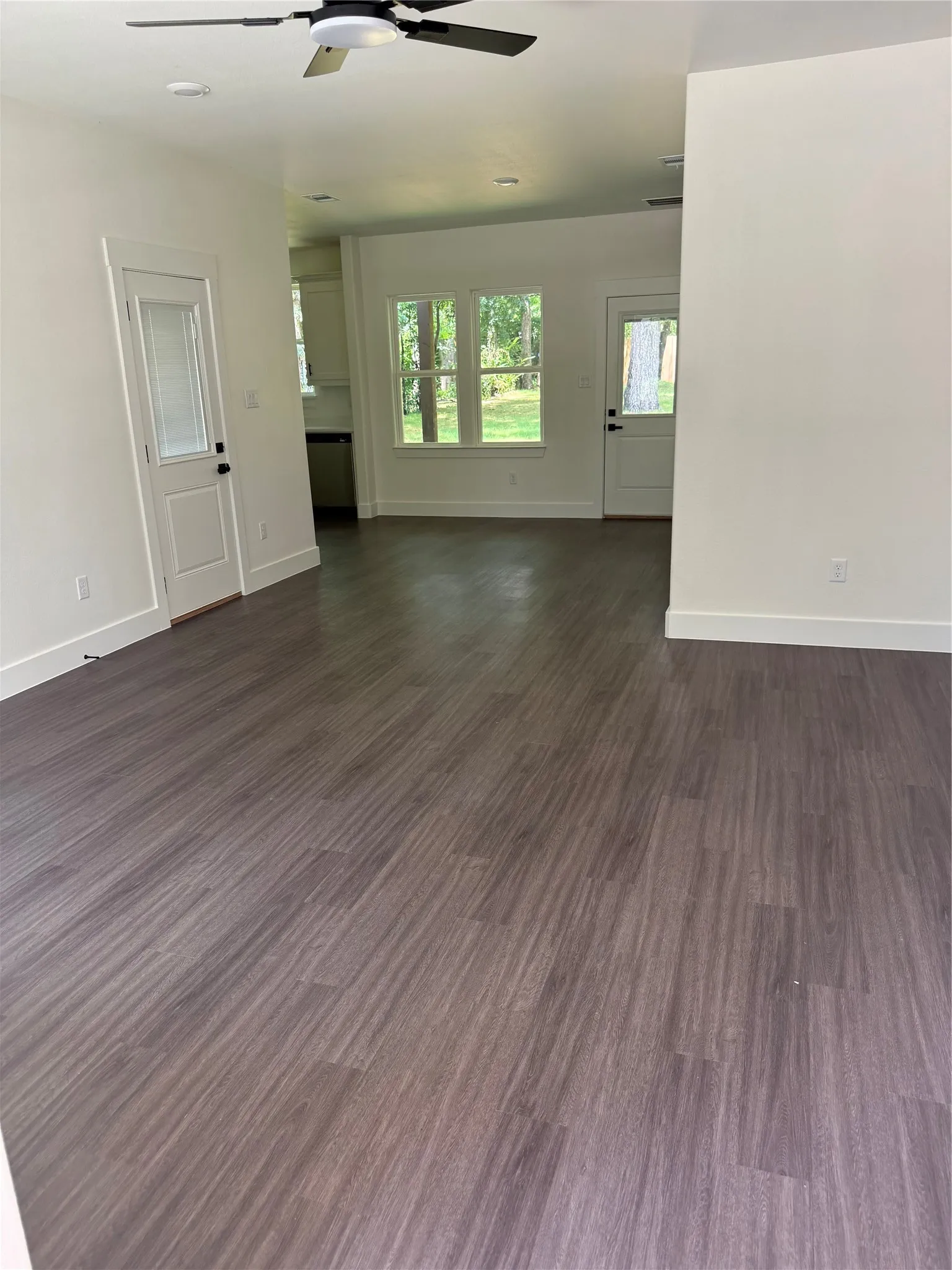 Spacious interior featuring wood-finish flooring, white walls, and a ceiling fan
