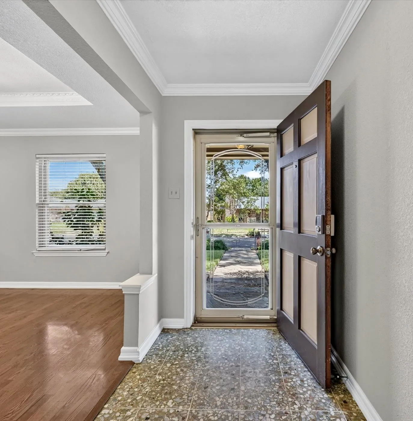 Welcoming entry with a heavy glass front door, Terrazzo tile, and rich wood flooring