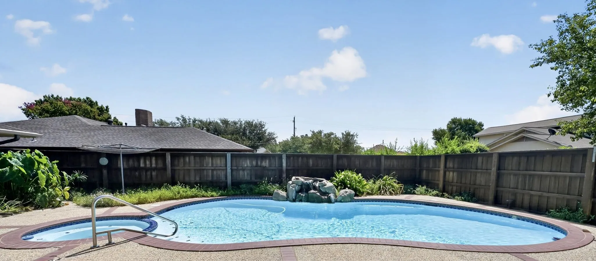 Resort-style backyard featuring a sparkling pool, spa, waterfall, and plenty of space for outdoor entertaining