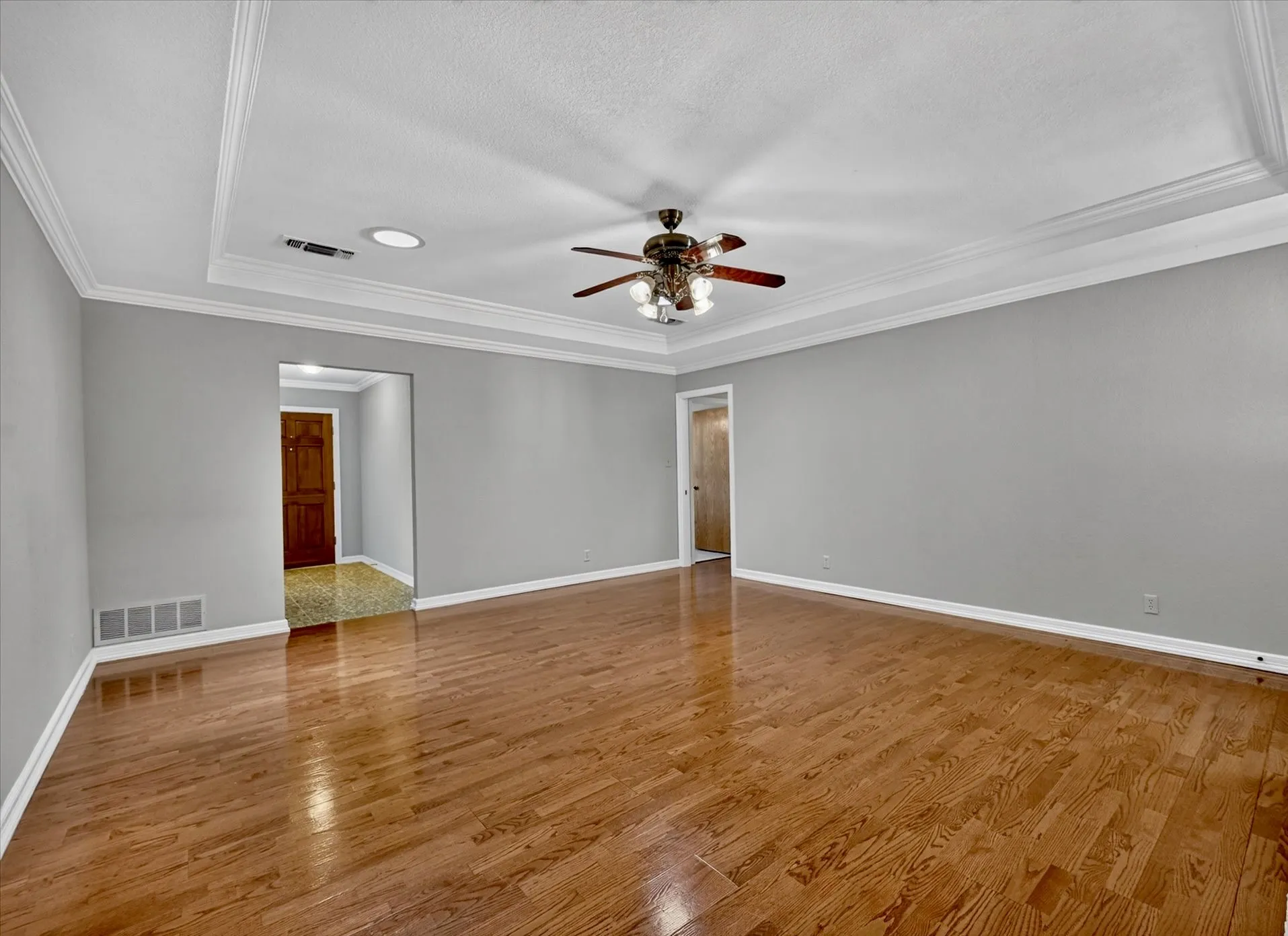 Living room with two ceiling lights for natural light and entries to front and bedroom hallways