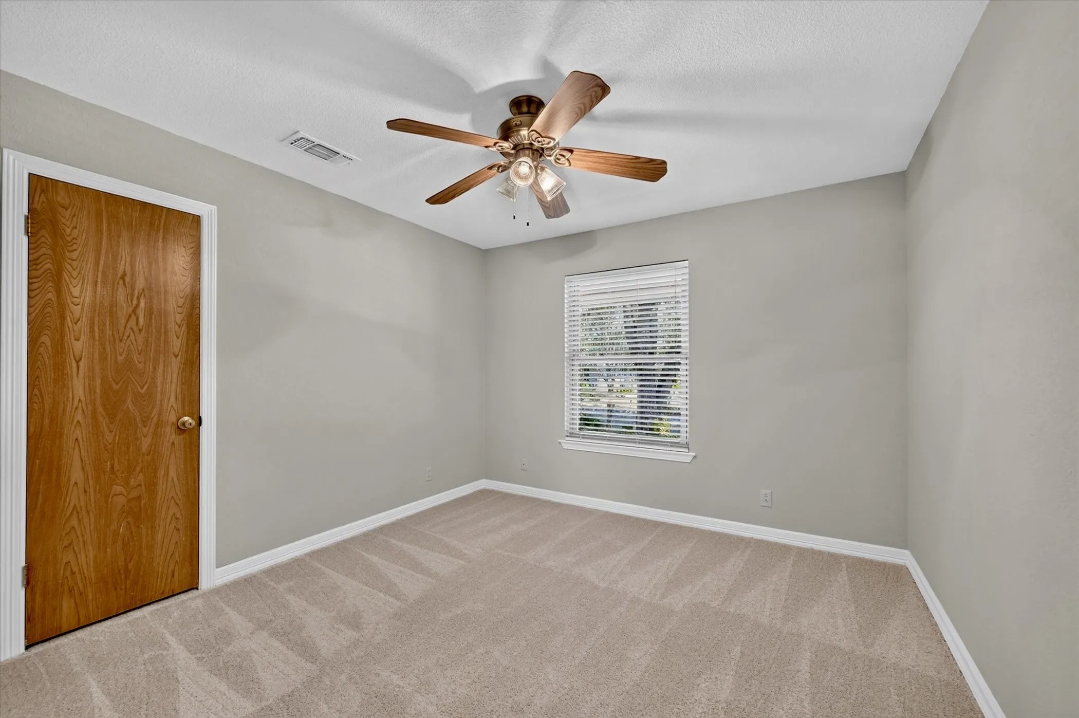 Spacious secondary bedroom with fresh carpet, neutral décor, and abundant natural light