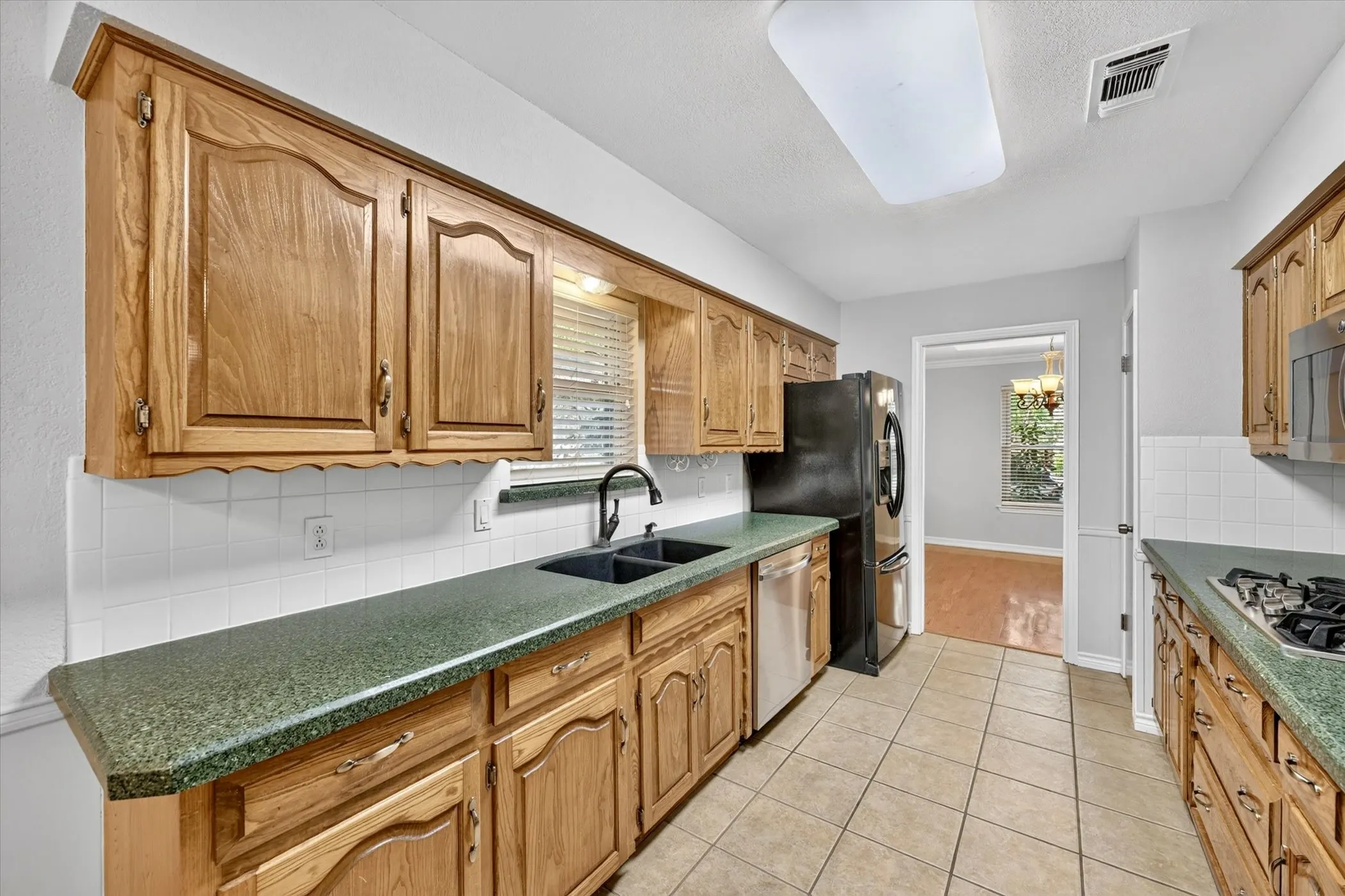 Galley kitchen including double oven, gas stove top, microwave oven, and refrigerator (conveys with home)