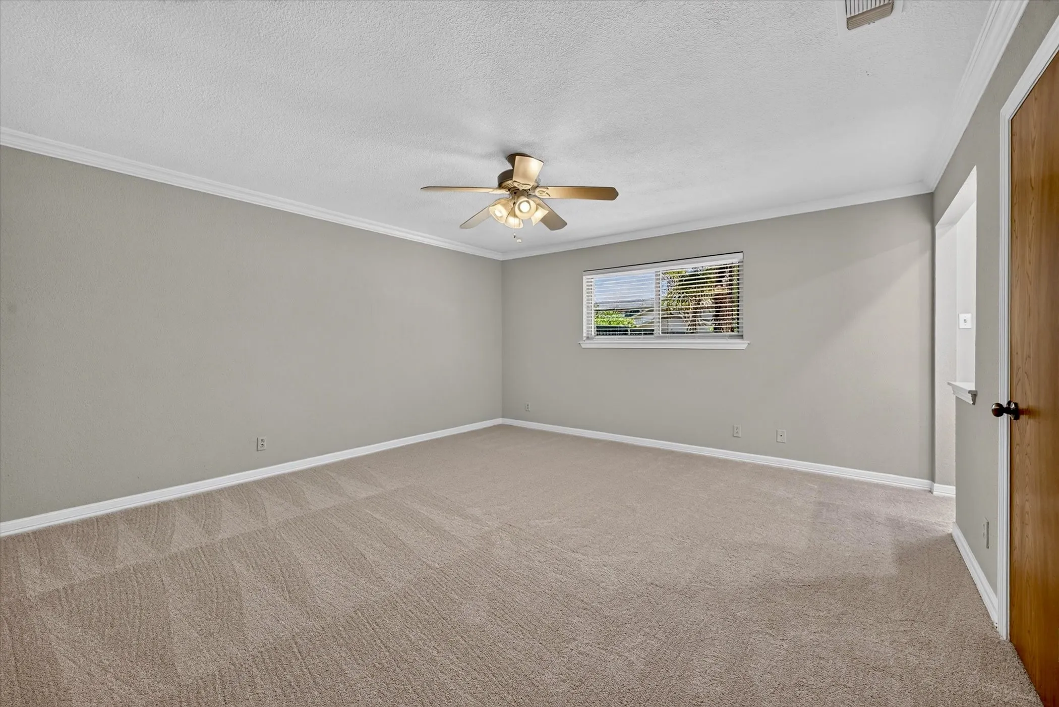Spacious primary suite with fresh carpet, ceiling fan, and private ensuite bath