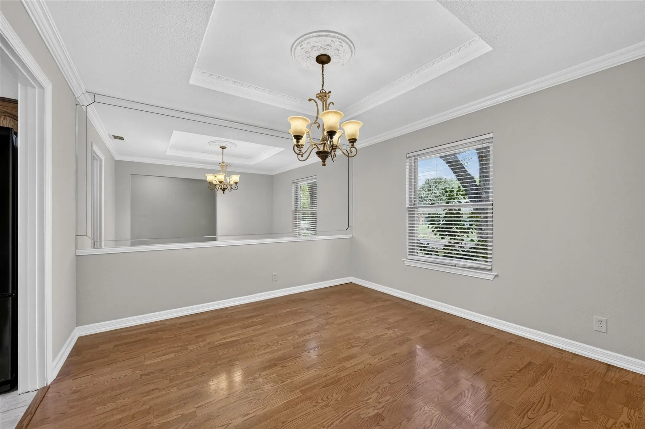 Formal dining room featuring tray ceilings, crown molding and wood flooring