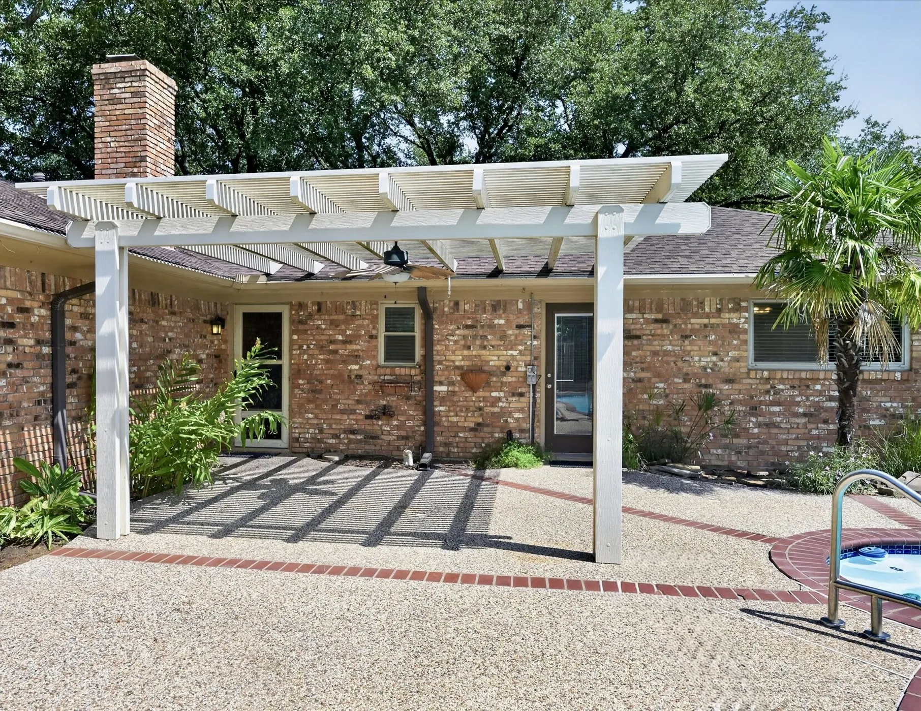 Covered pergola offers a shaded outdoor living area overlooking the pool and spa, and beautifully landscaped backyard