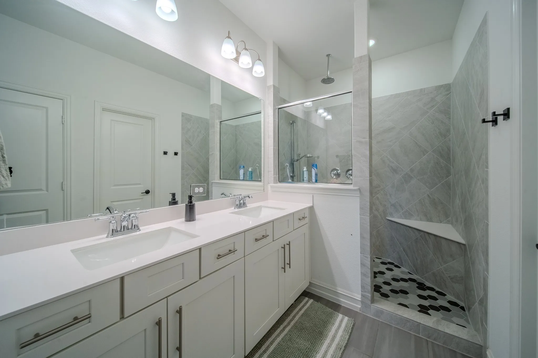 Dual vanity with white cabinetry, polished chrome fixtures, and a large mirror