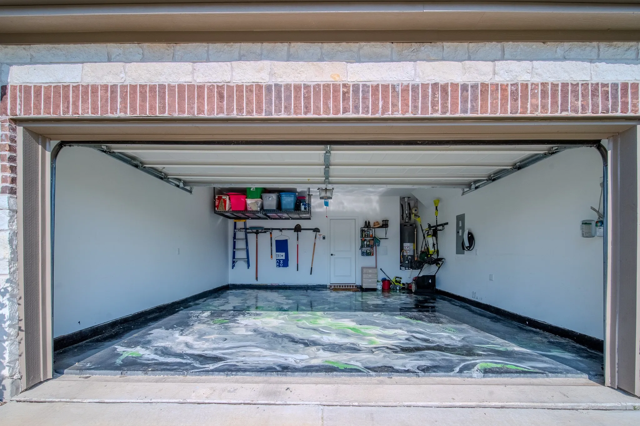 Two-car garage featuring a decorative epoxy floor finish and white painted walls