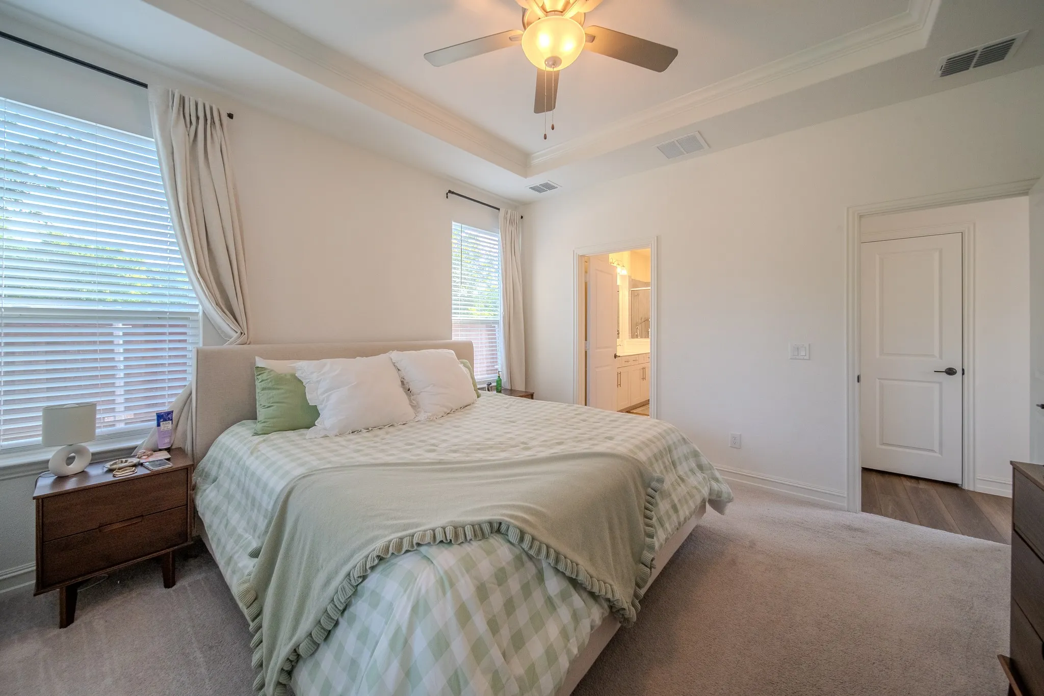 Bedroom featuring a tray ceiling with a built-in ceiling fan and light fixture