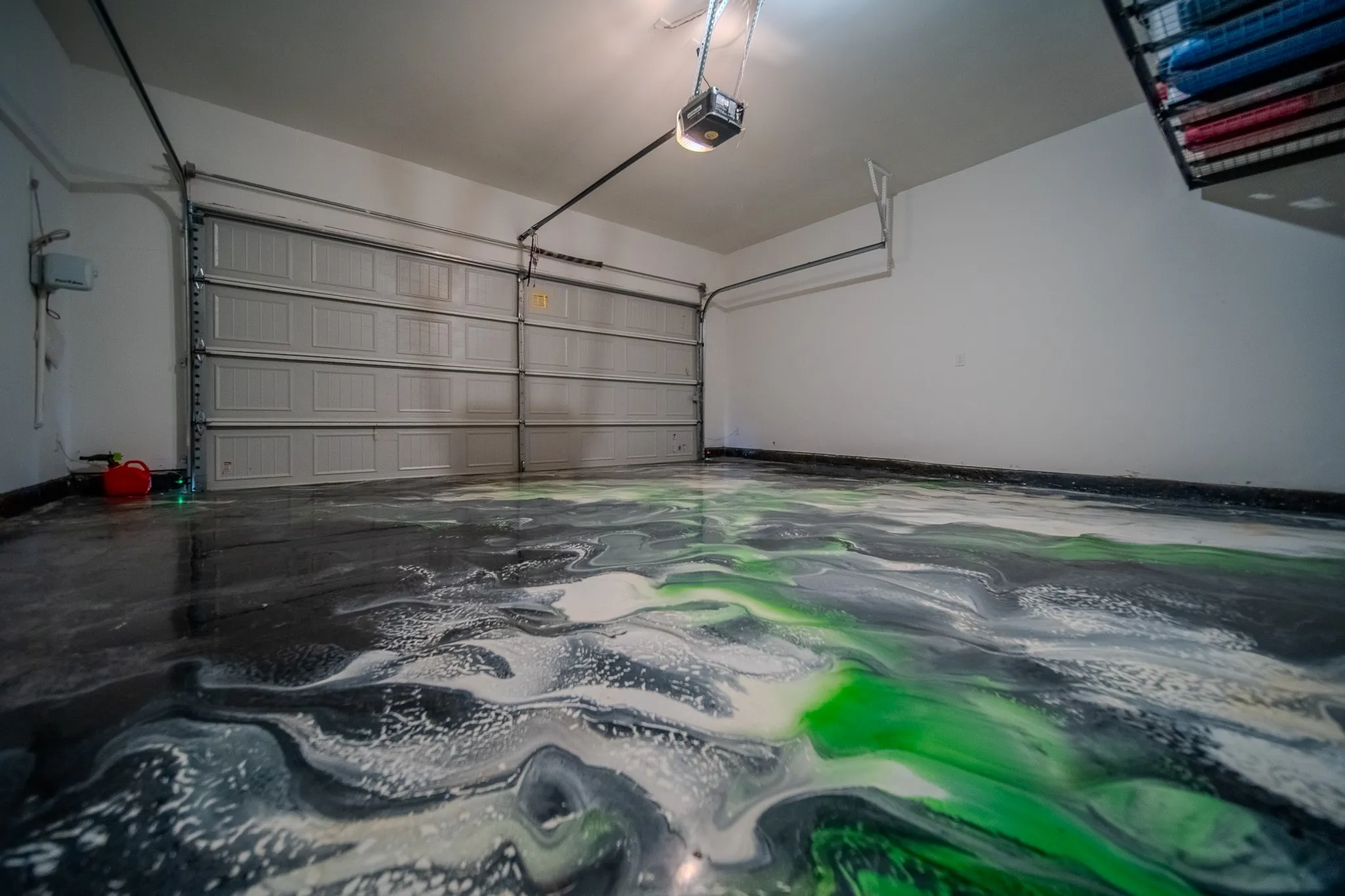 Garage featuring a decorative epoxy floor, overhead lighting, and a paneled garage door