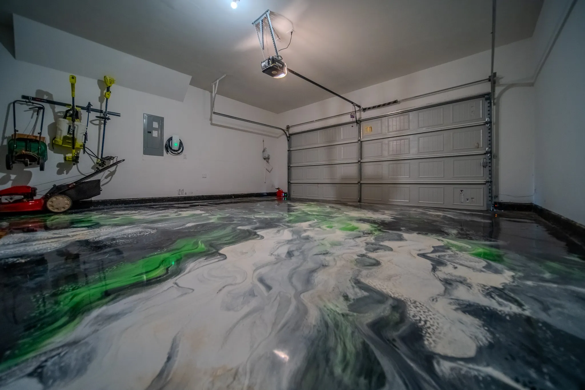 Garage featuring a patterned epoxy floor in white, black, and green tones