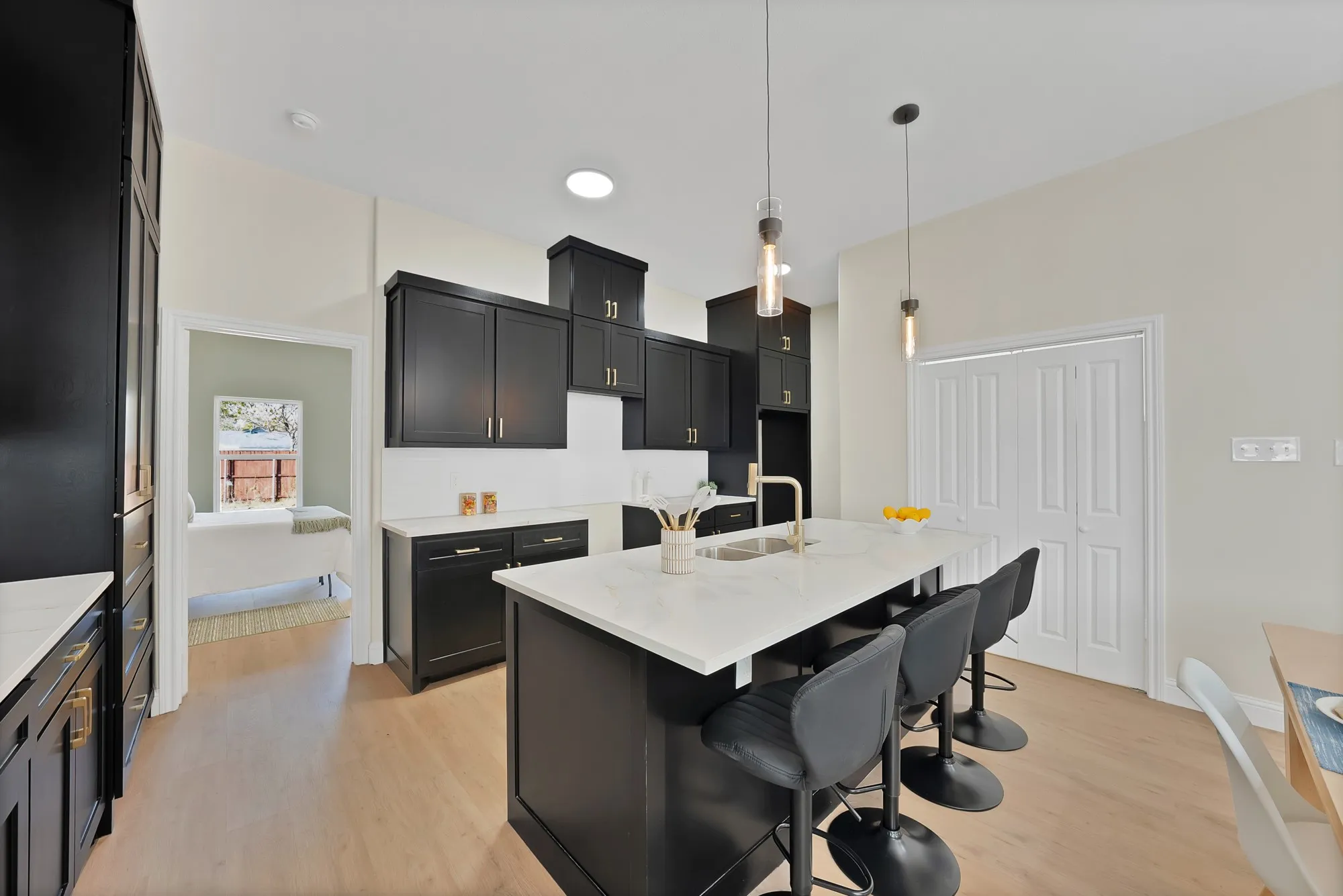 Contemporary kitchen featuring dark cabinetry, light-toned wood-finish flooring, and a central island with a white countertop