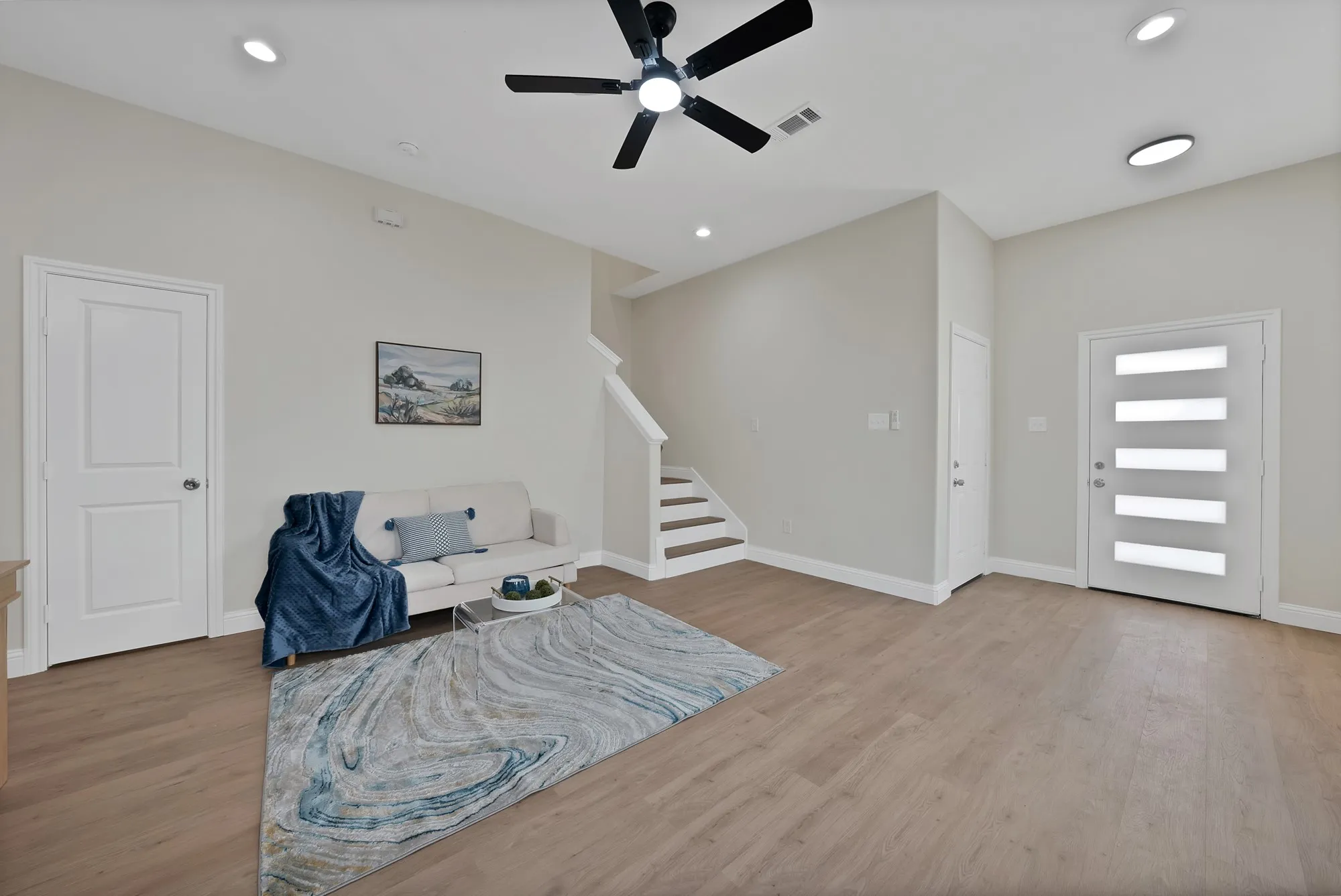 Bright living area featuring wood-finish flooring, recessed lighting, and a modern ceiling fan
