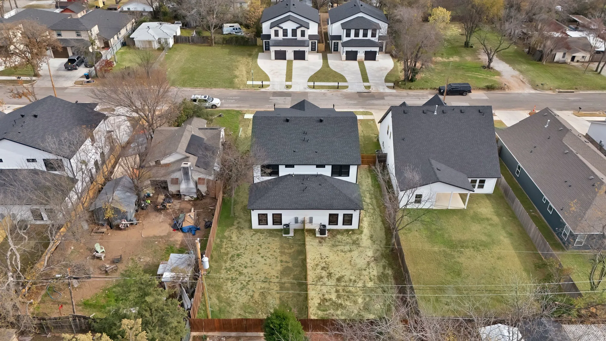 White two-story residence featuring a dark shingle roof, a rear patio, and a fenced backyard