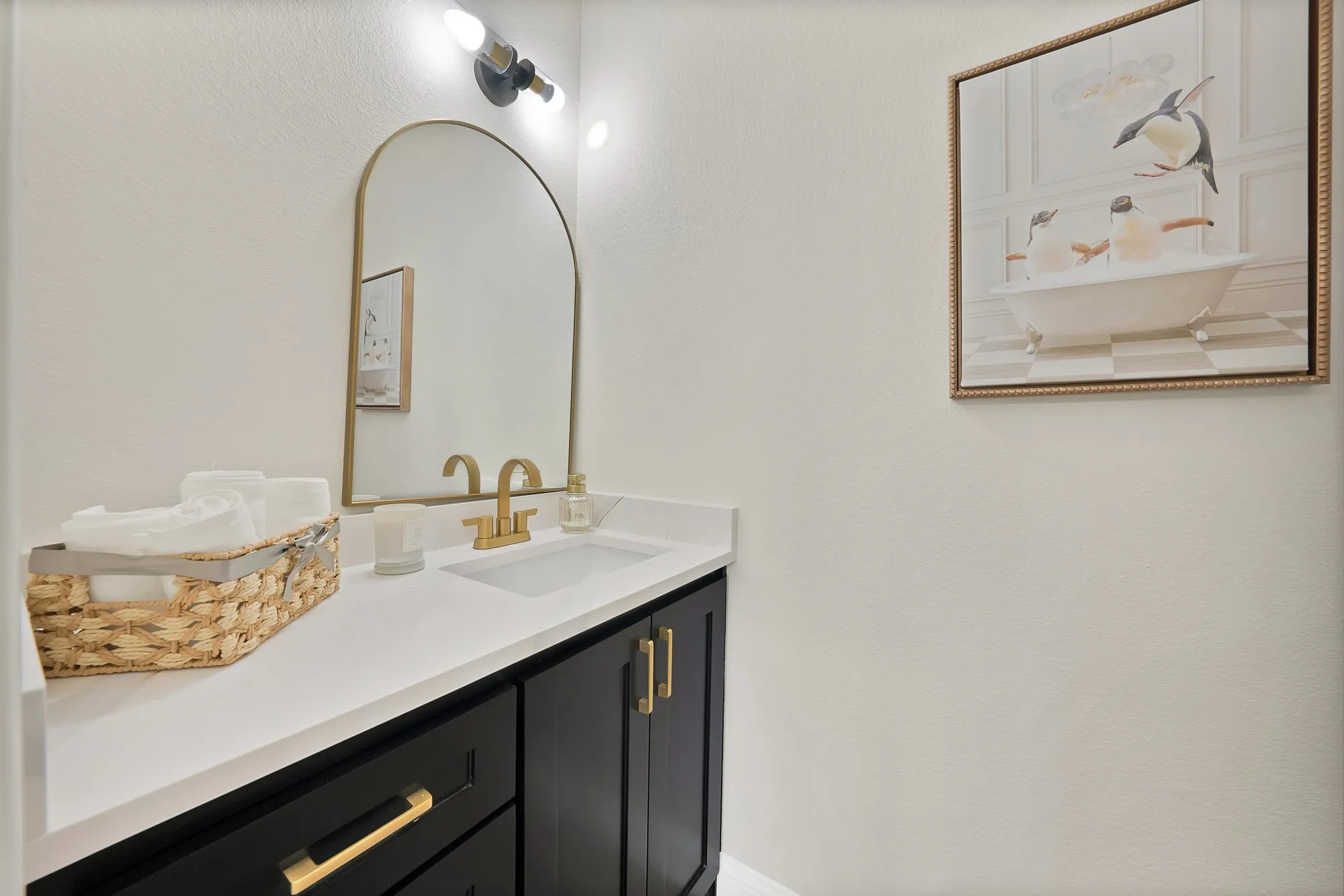 Bathroom vanity featuring a white countertop, undermount sink, and brass-finish faucet
