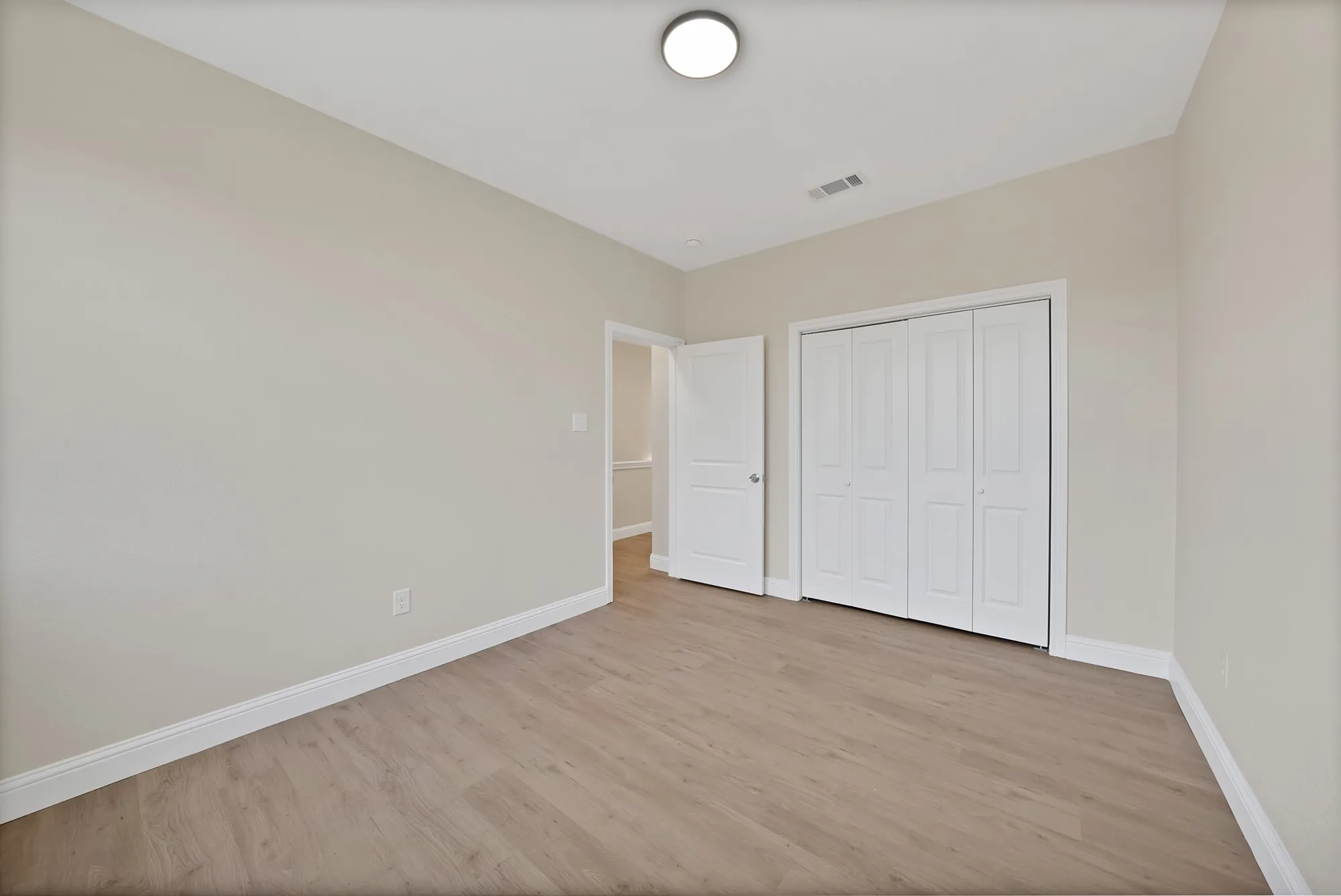 Bedroom featuring wood-finish flooring, neutral wall paint, white baseboards, and a white bi-fold closet
