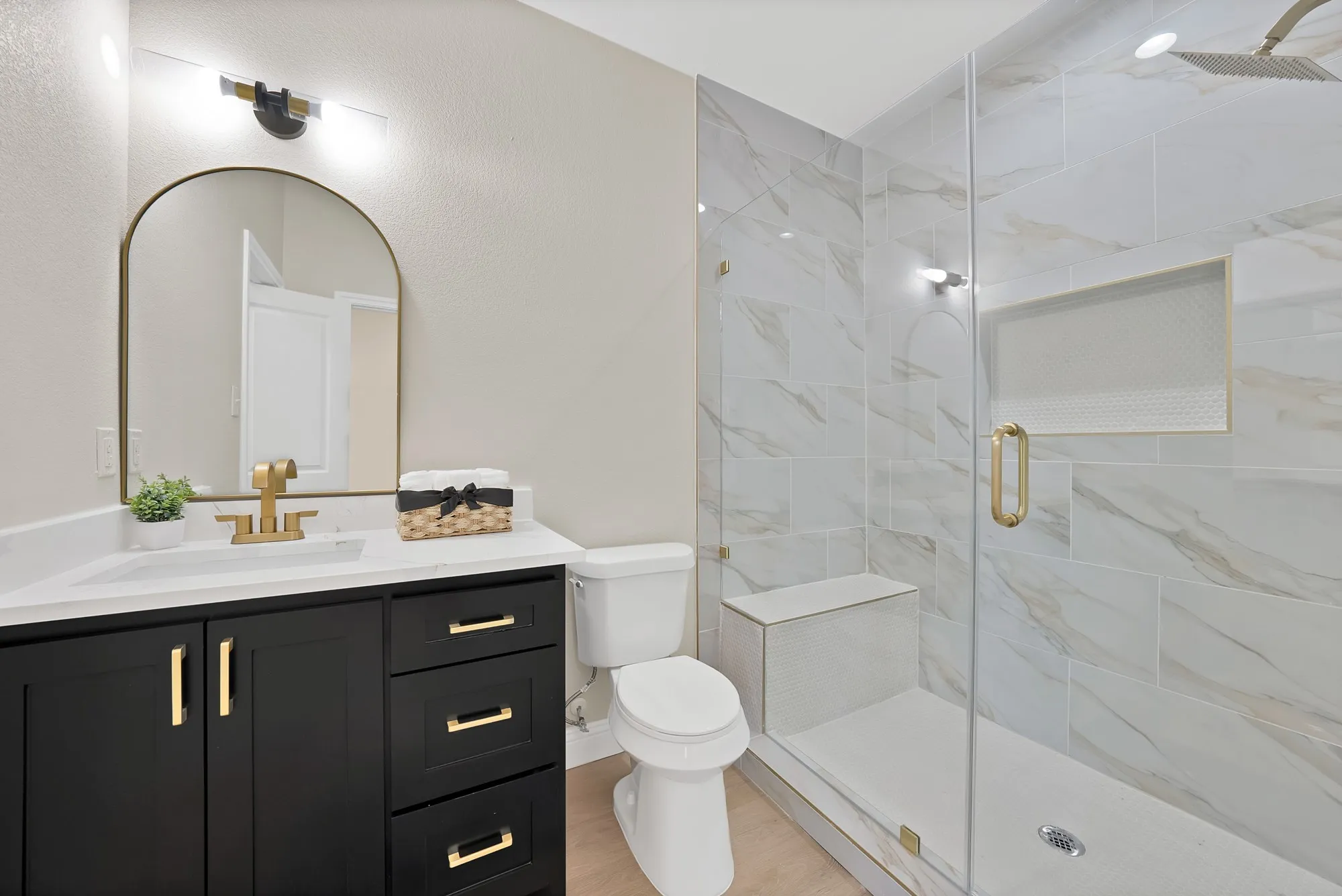 Contemporary bathroom featuring a spacious glass-enclosed shower with large format marble-look tile, a built-in bench, and an integrated niche