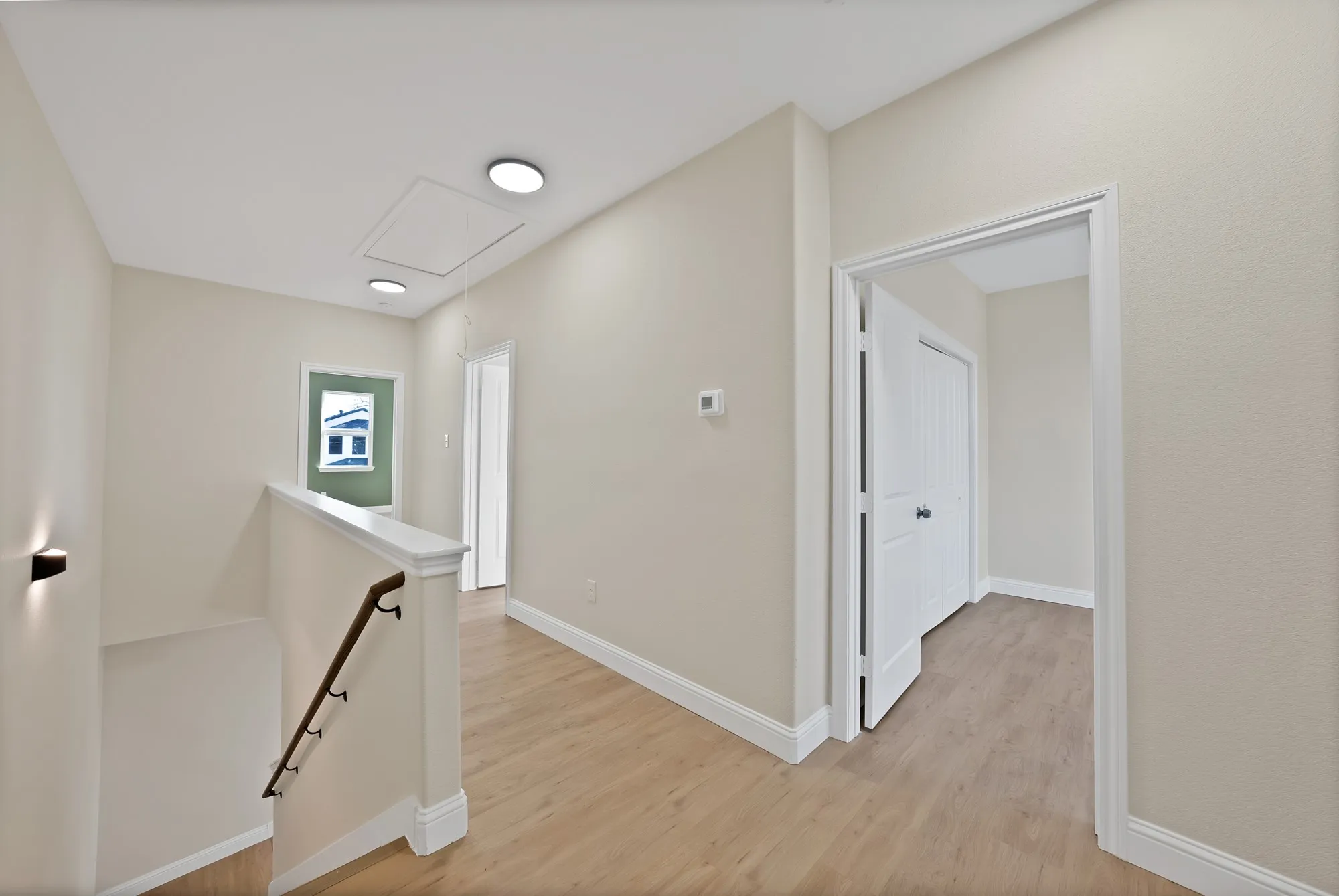 Hallway with wood-finish flooring, white baseboards, and neutral wall paint