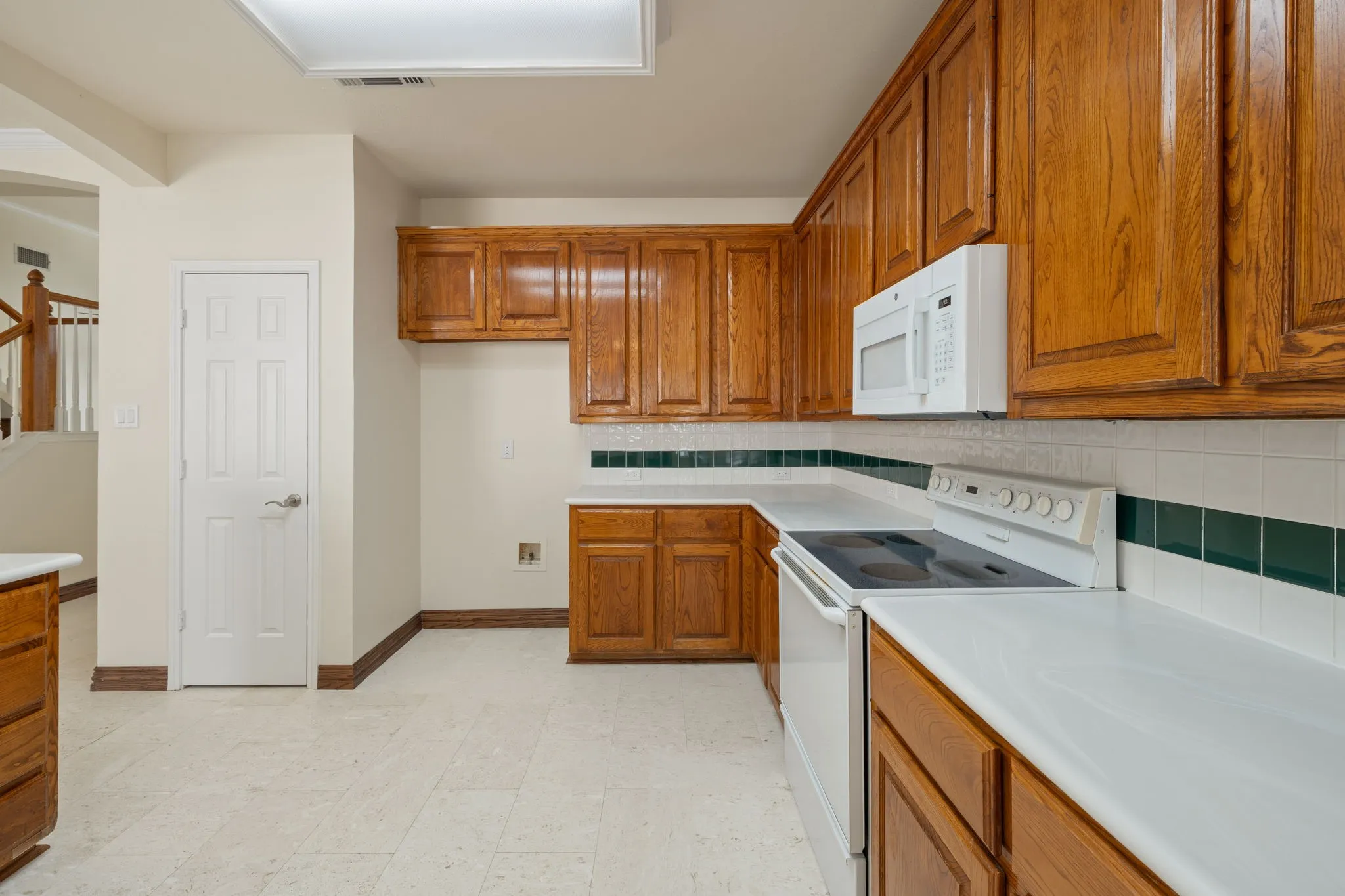 Kitchen featuring wood cabinetry, white countertops, a built-in microwave, an electric range, and a two-tone tile backsplash