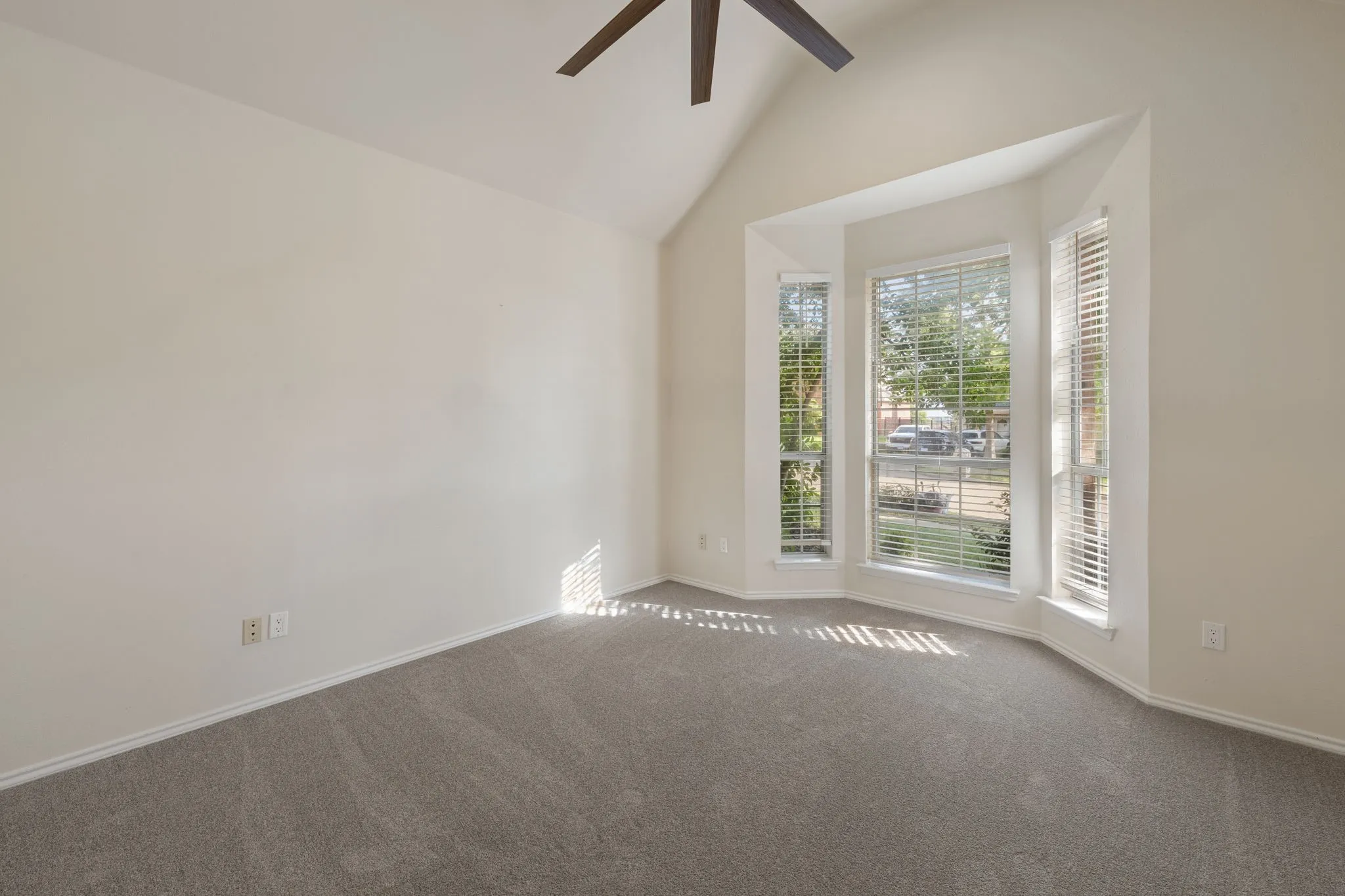 Room featuring a bay window, vaulted ceiling, and ceiling fan