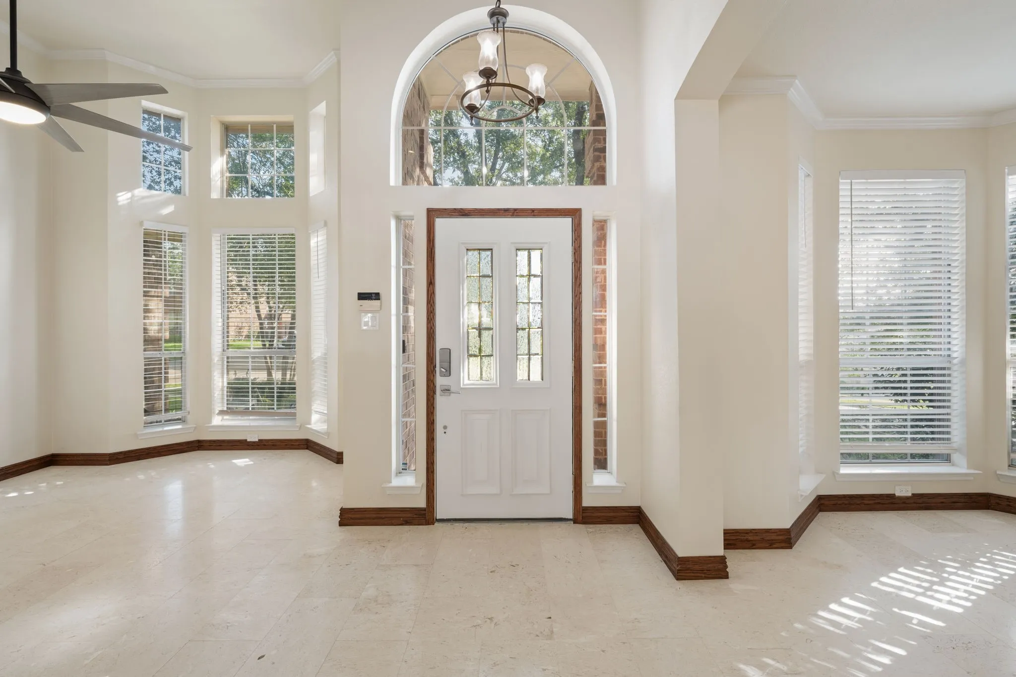 Entryway featuring a white paneled door with leaded glass, an arched transom window, and a chandelier-style light fixture