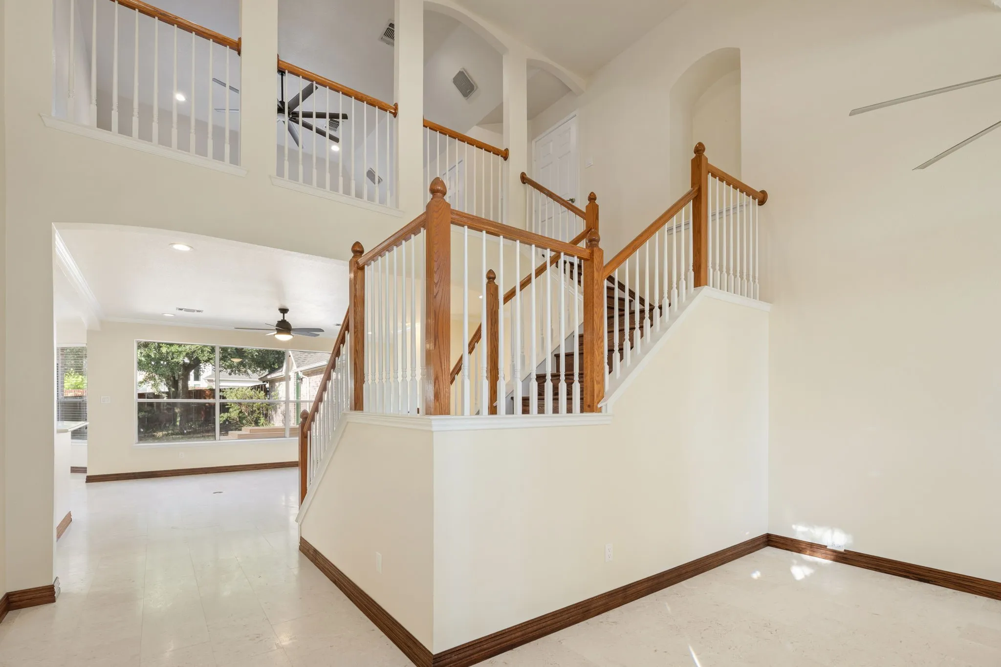 Two-story interior featuring a wood-finish staircase with white balusters, wood-finish baseboards, and light-toned flooring