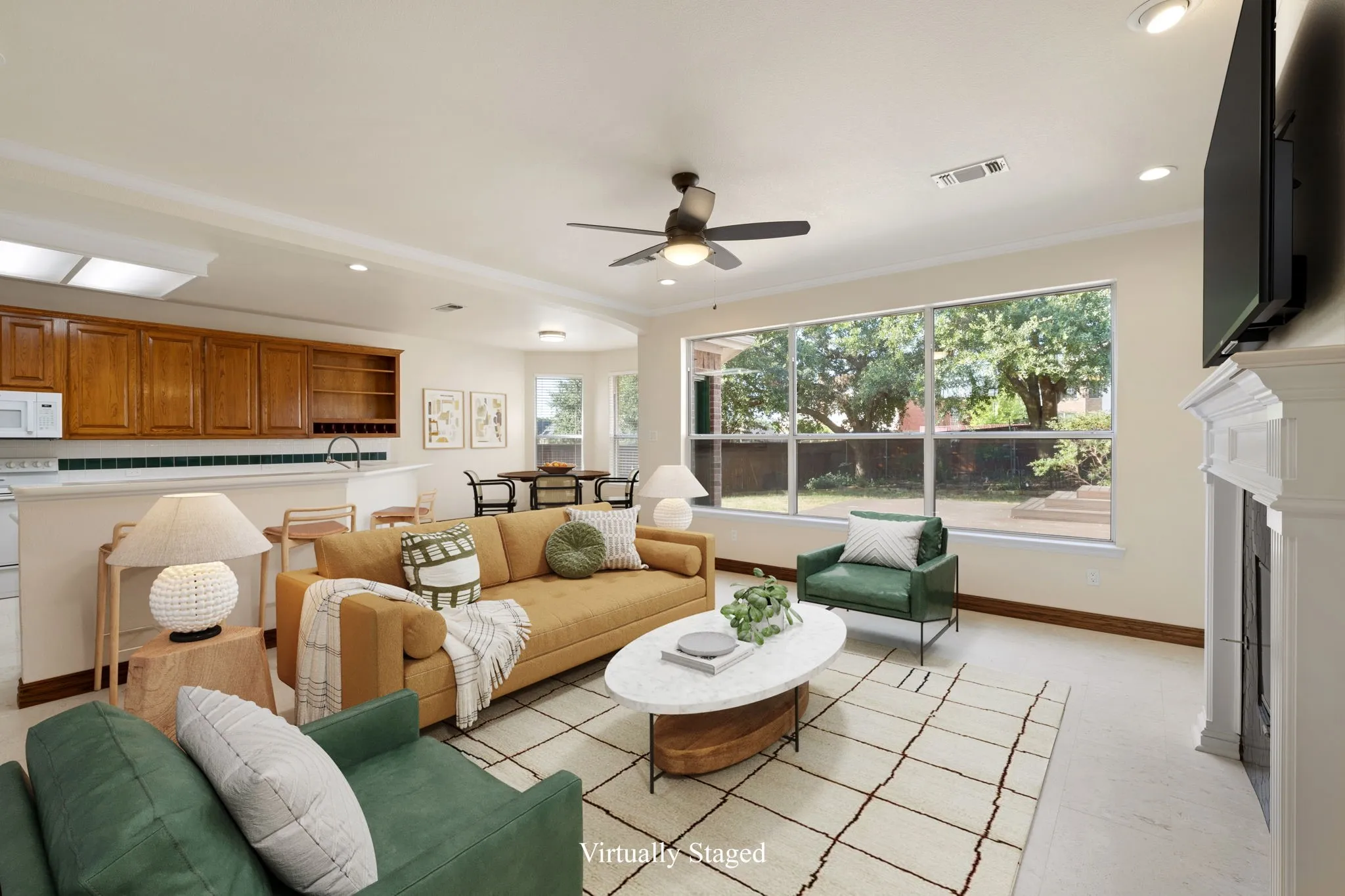 Downstairs living area featuring a central ceiling fan, large windows, and a built-in fireplace with a detailed mantel