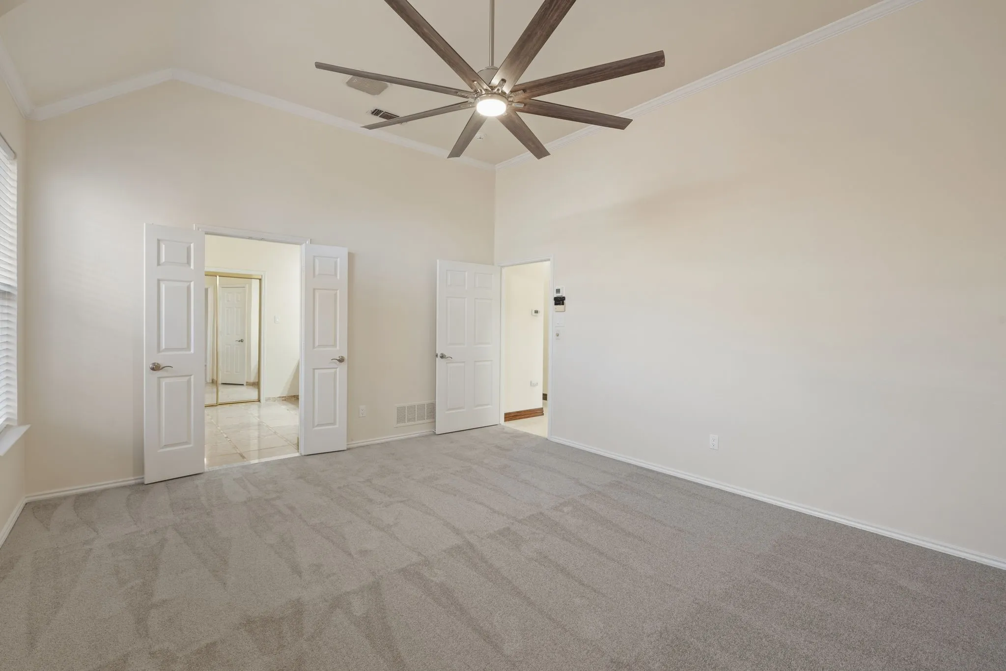 Primary bedroom  without staging
featuring vaulted ceilings, crown molding, and a modern ceiling fan