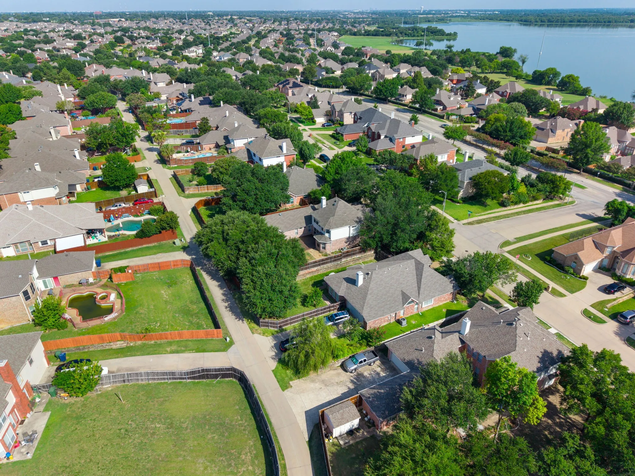 Residential neighborhood with mature trees and a substantial body of water in the background