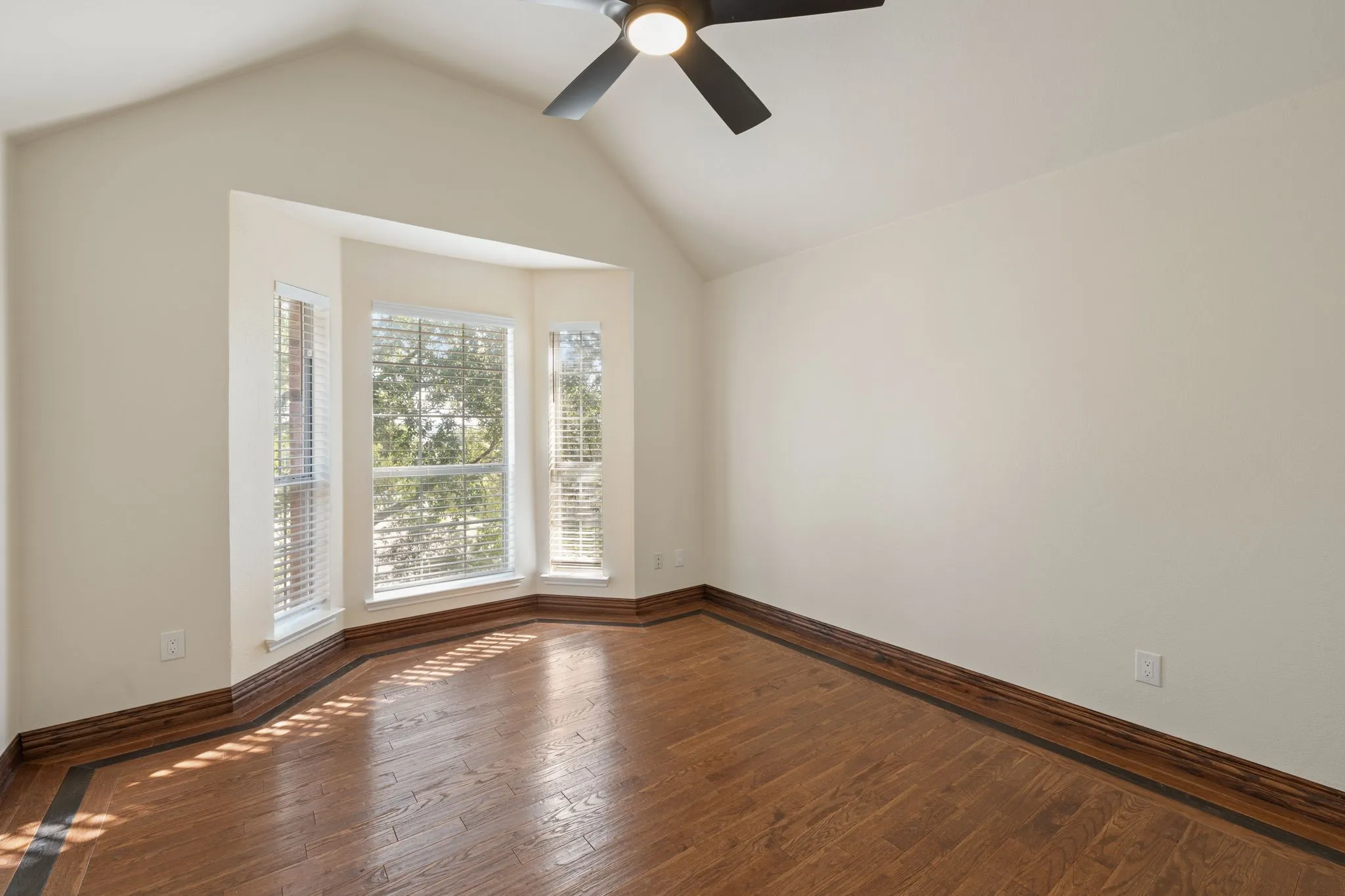 Room featuring a vaulted ceiling and bay windows with white blinds
