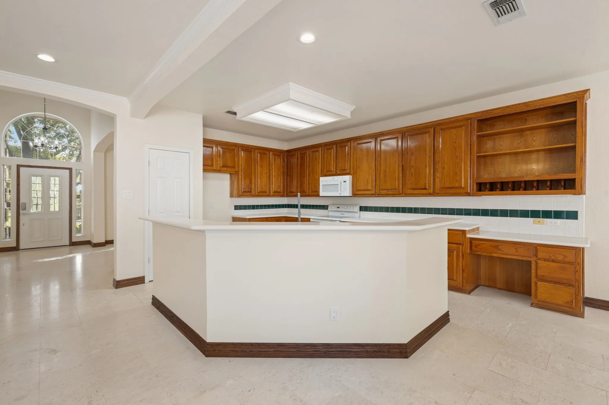 Kitchen featuring a central island, light wood cabinetry, and a built-in desk area