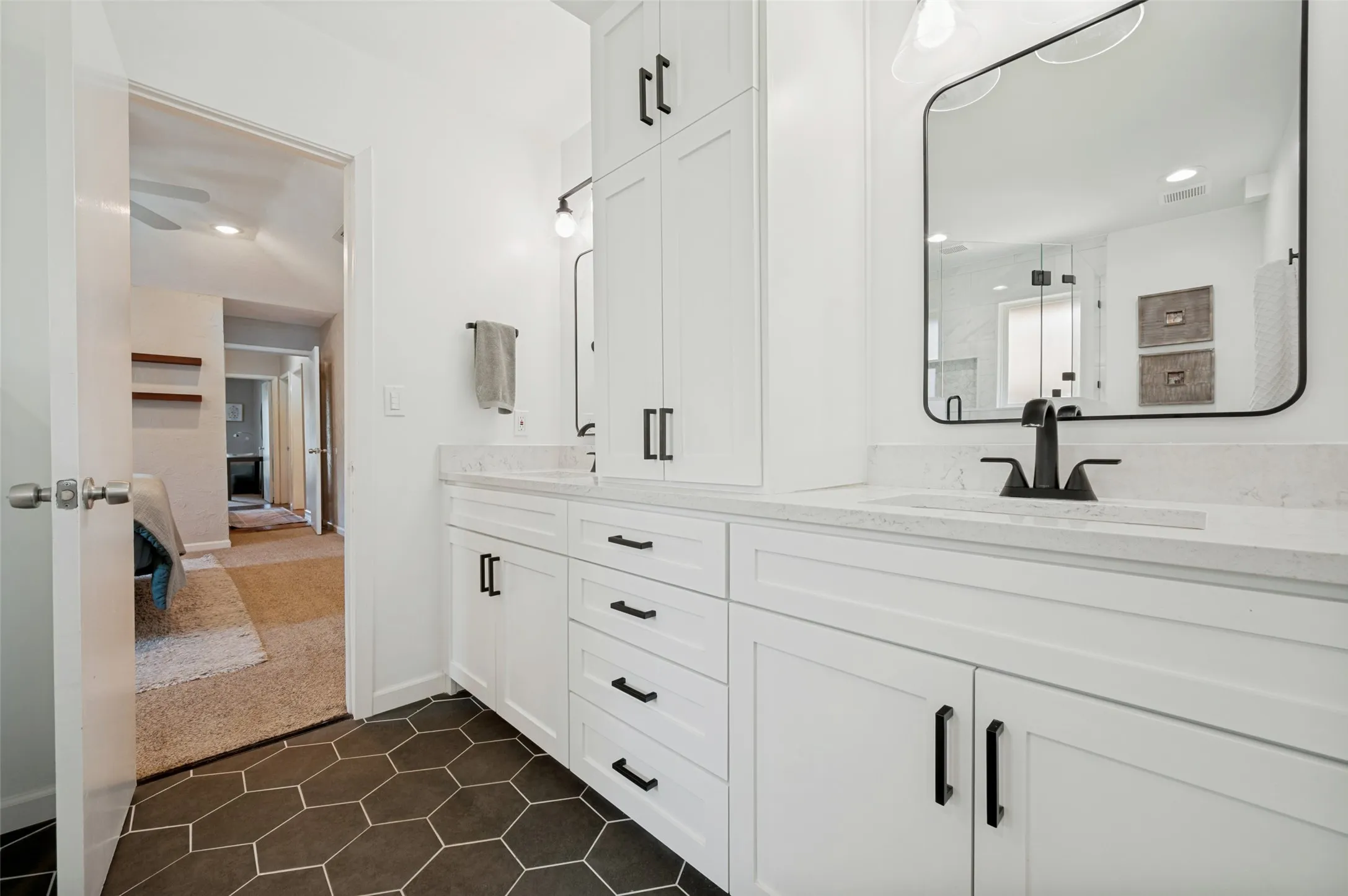 Bathroom featuring a dual vanity with white cabinetry and black hardware